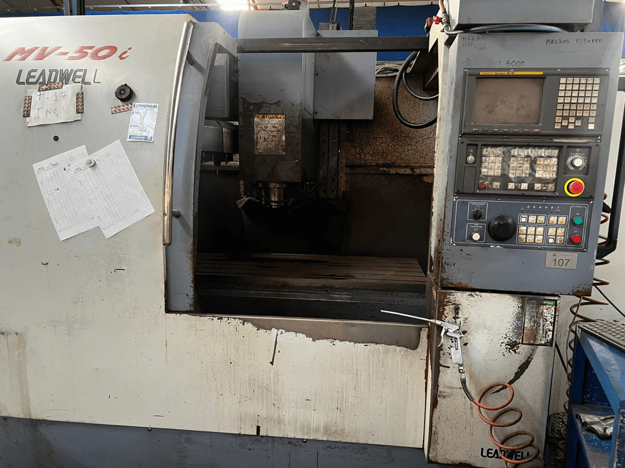 Verticaal bewerkingscentrum Leadwell MV-50i, vooraanzicht, met het bedieningspaneel, het spindelgedeelte en de werktafel met slijtage.