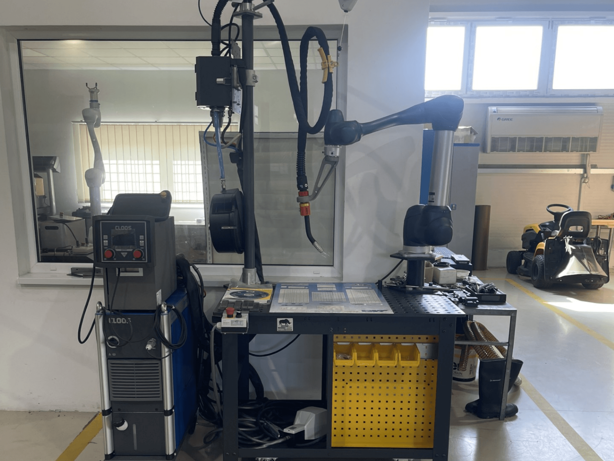 DOOSAN M1013-samenwerkingsrobot in een werkplaats, zijaanzicht met lasapparatuur en gereedschap op een werkbank.