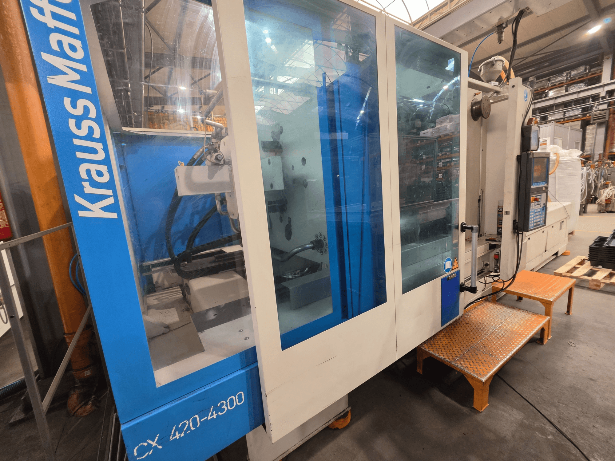 Krauss Maffei CX 420-4300 hydraulische spuitgietmachine, zijaanzicht met bedieningspaneel en transparante panelen.