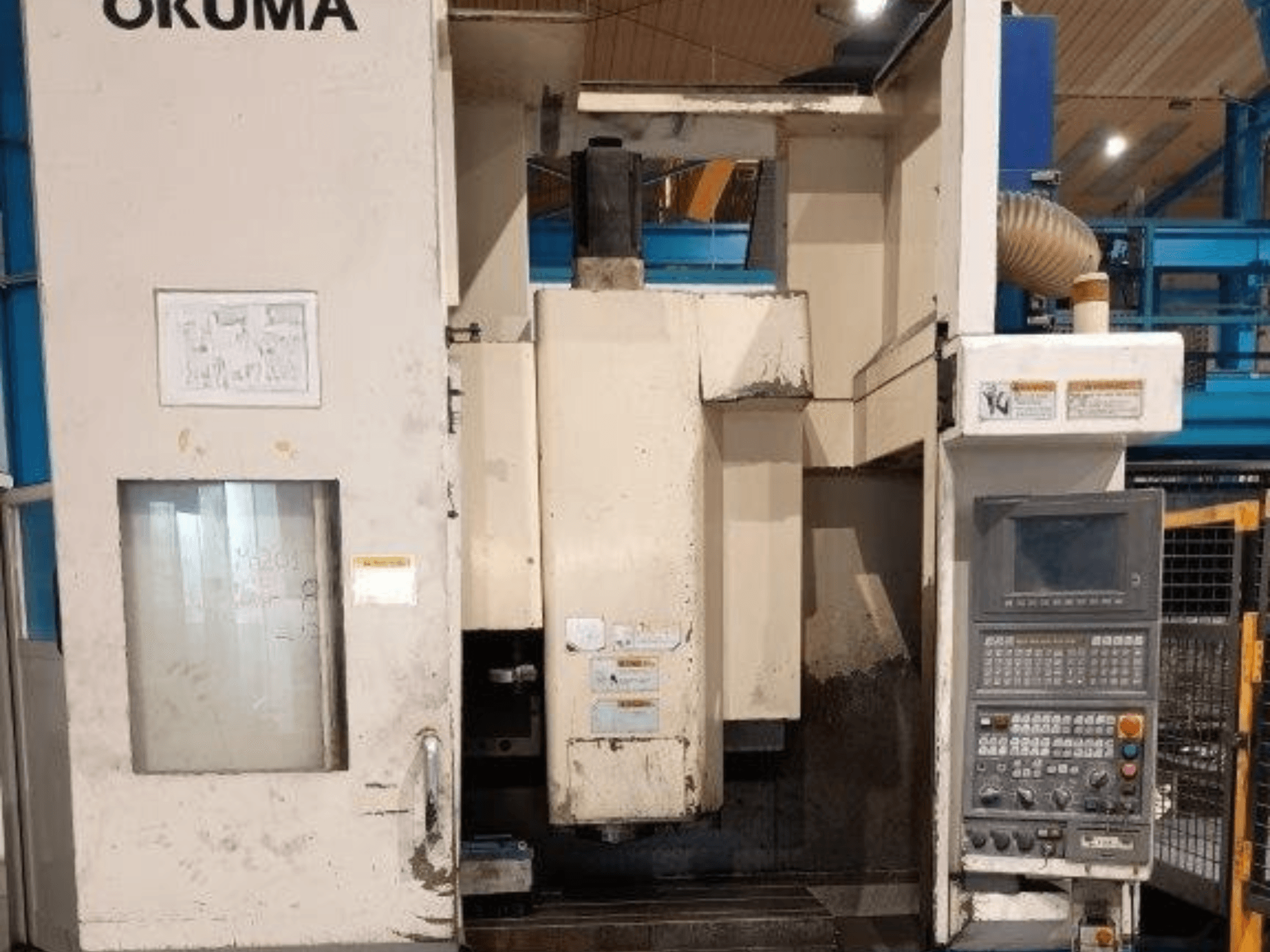 Okuma CNC freesmachine, vooraanzicht, met bedieningspaneel met knoppen, display en zichtbare markeringen op de machinebehuizing.
