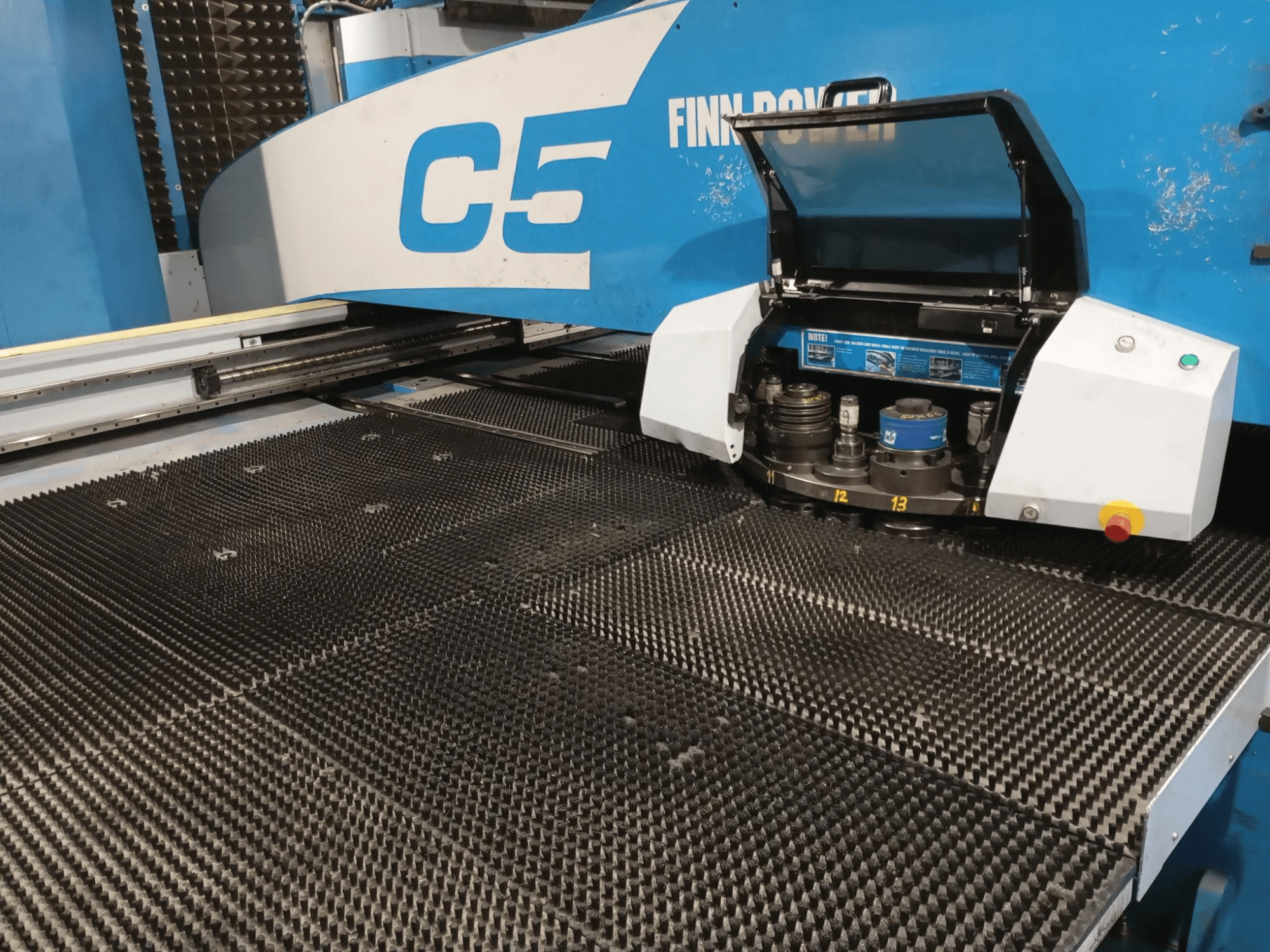Finn-Power C5 ponsmachine, vooraanzicht, met de gereedschapskop open over een gestructureerde werktafel met genummerde indexeringspunten.
