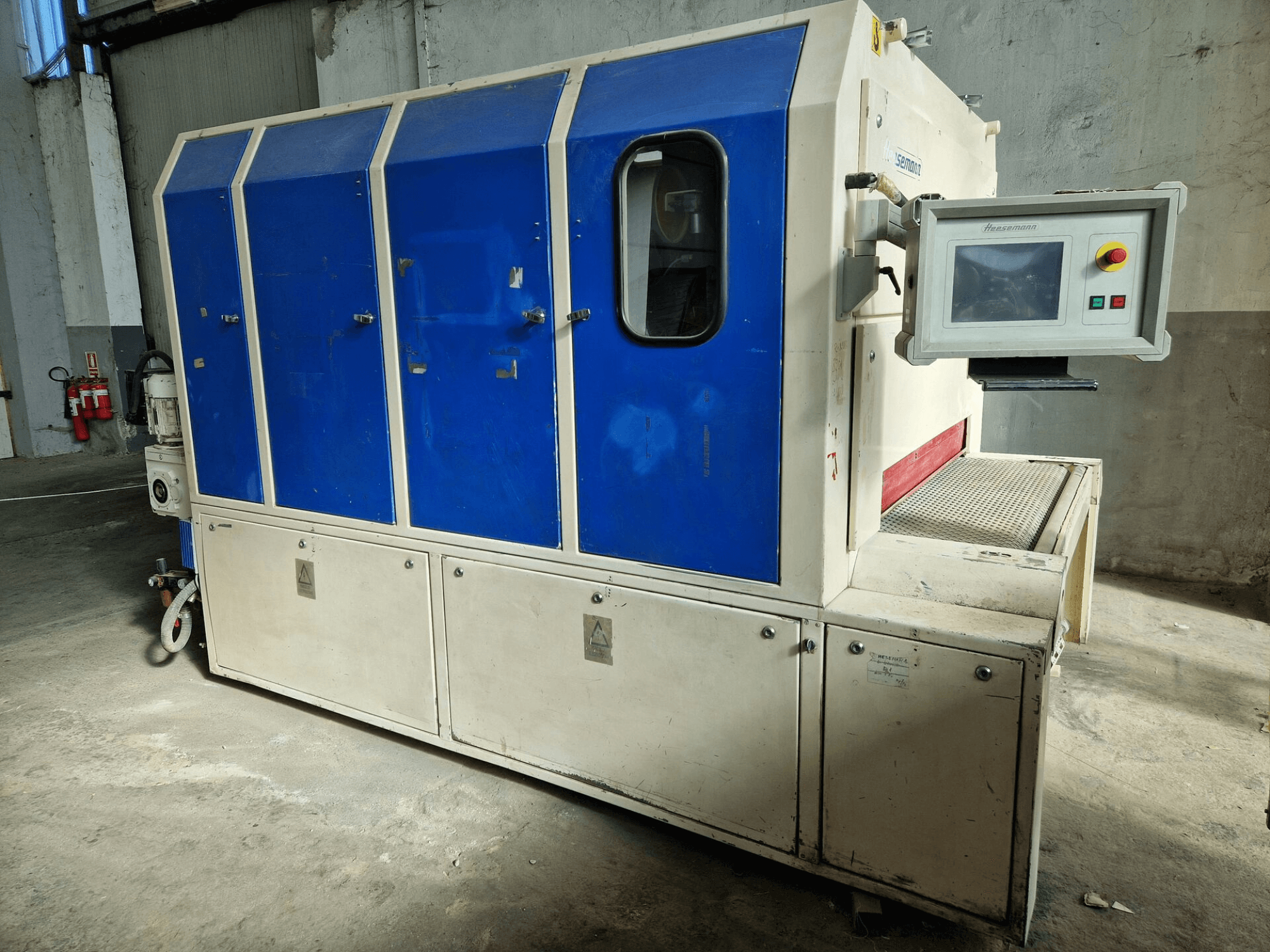 Industriële machine van het merk "Sedecom", zijaanzicht; heeft blauwe panelen, een bedieningsscherm en een gestructureerd oppervlak voor het hanteren van producten.