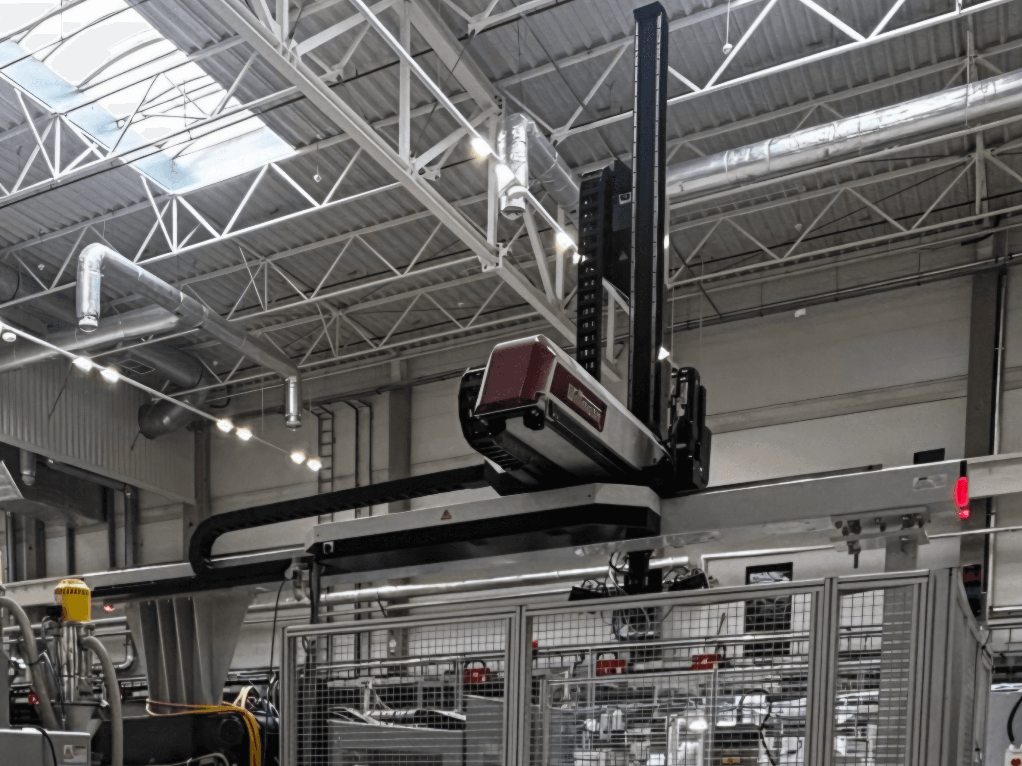 WITTMANN W832PRO-kunststofverwerkingsmachine in een fabrieksomgeving, zijaanzicht met het bovenliggende systeem en de industriële achtergrond.