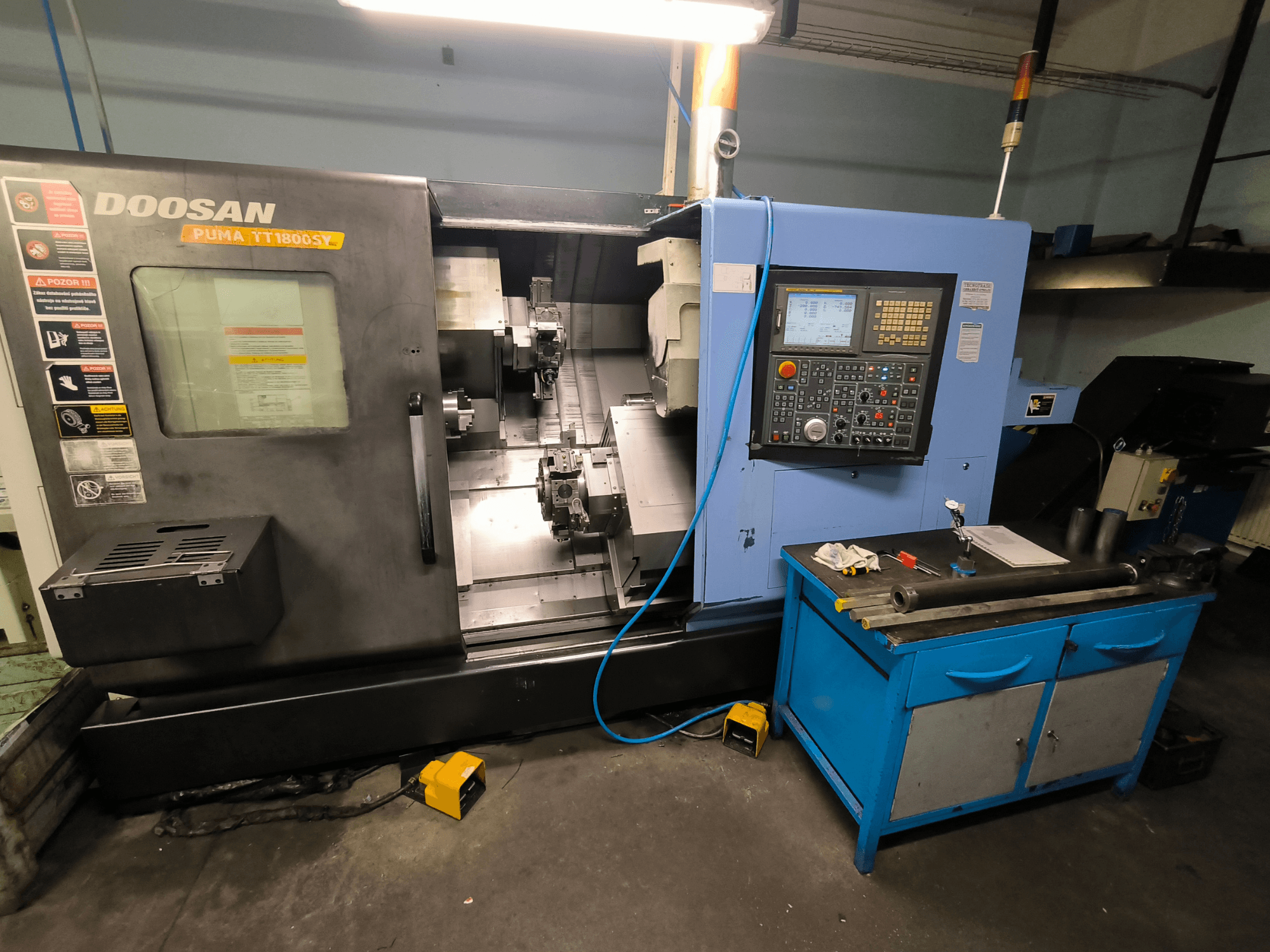 Doosan Puma TT1800SY CNC draaibank, vooraanzicht, met bedieningspaneel, werkgebied met gereedschappen en machineonderdelen.