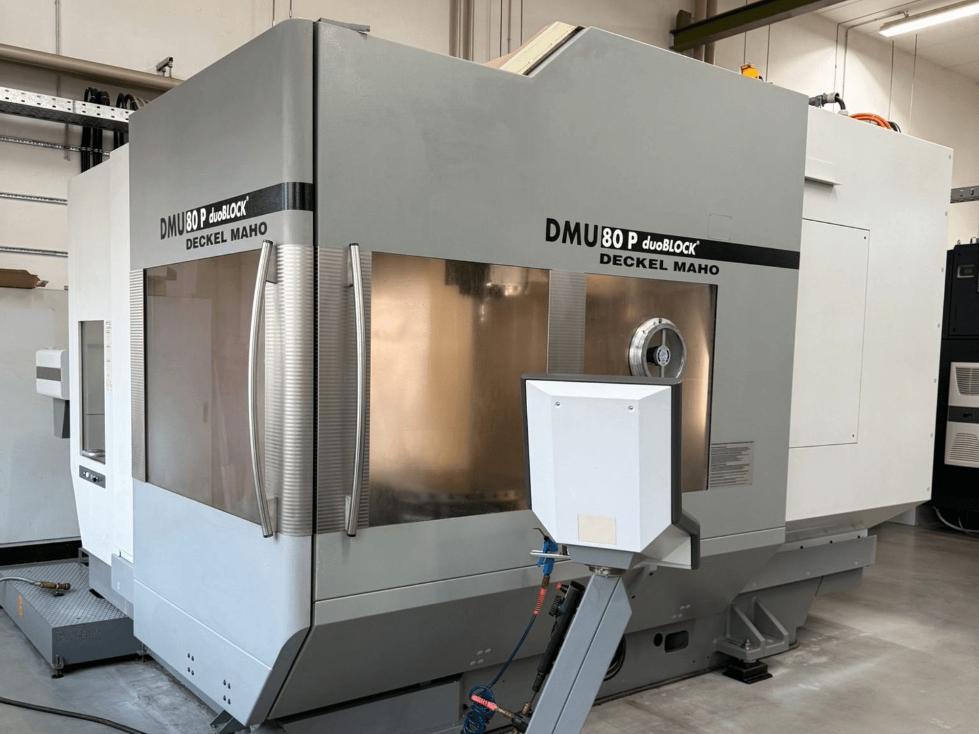 DMU 80 P duoBLOCK van Deckel Maho, vooraanzicht met de functies van het bewerkingscentrum en de besturingsinterface in een industriële omgeving.
