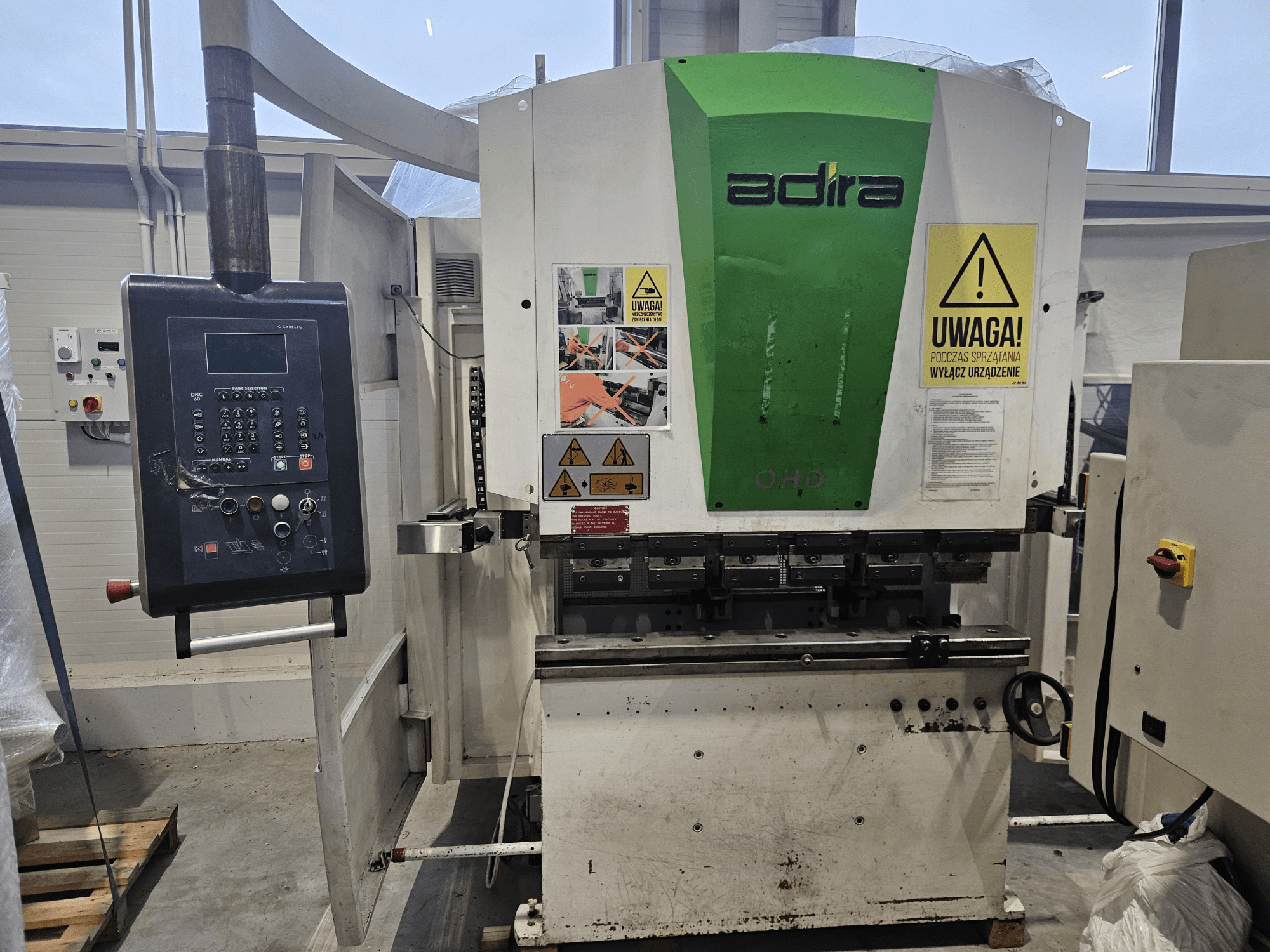 Adira OHD machine gezien vanaf de voorkant, met een bedieningspaneel, veiligheidswaarschuwingen en bedieningsknoppen.