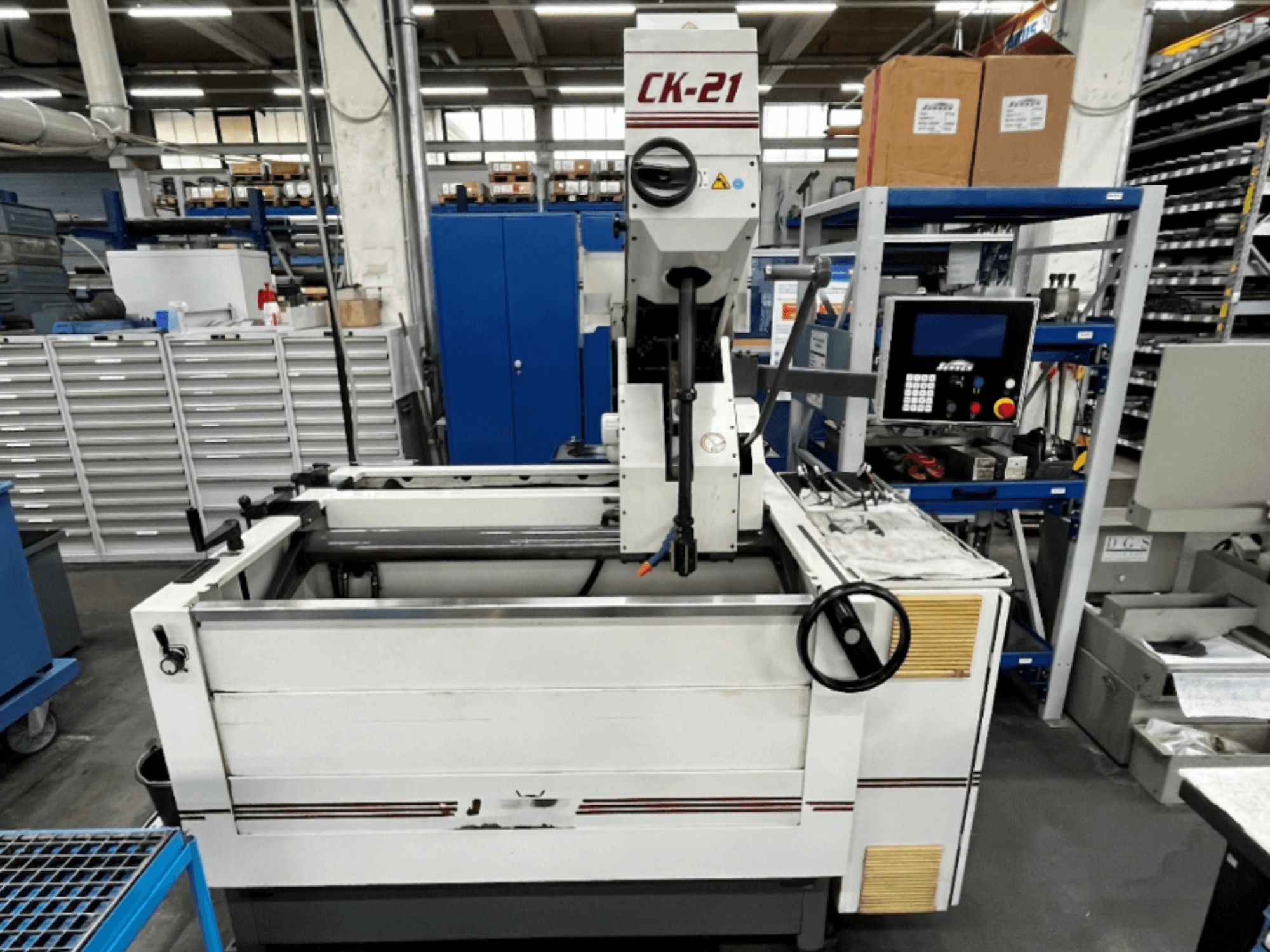 Sunnen CK-21-CC verticale hoonmachine in vooraanzicht, met bedieningselementen, hoongebied en ondersteunende apparatuur op de achtergrond.