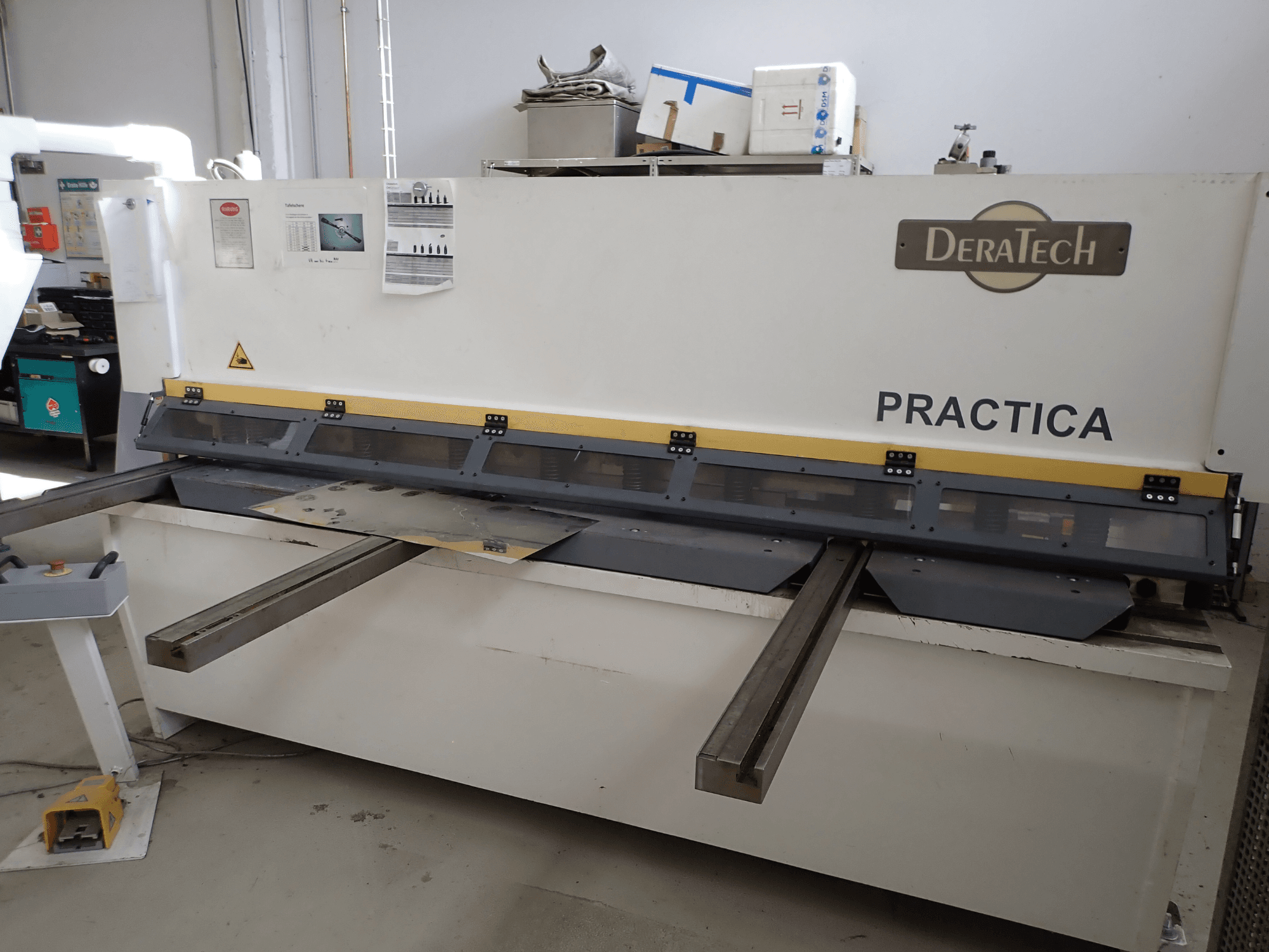 DERATECH Practica CNC snijmachine, vooraanzicht, met snijmes en metalen platen op het werkvlak.