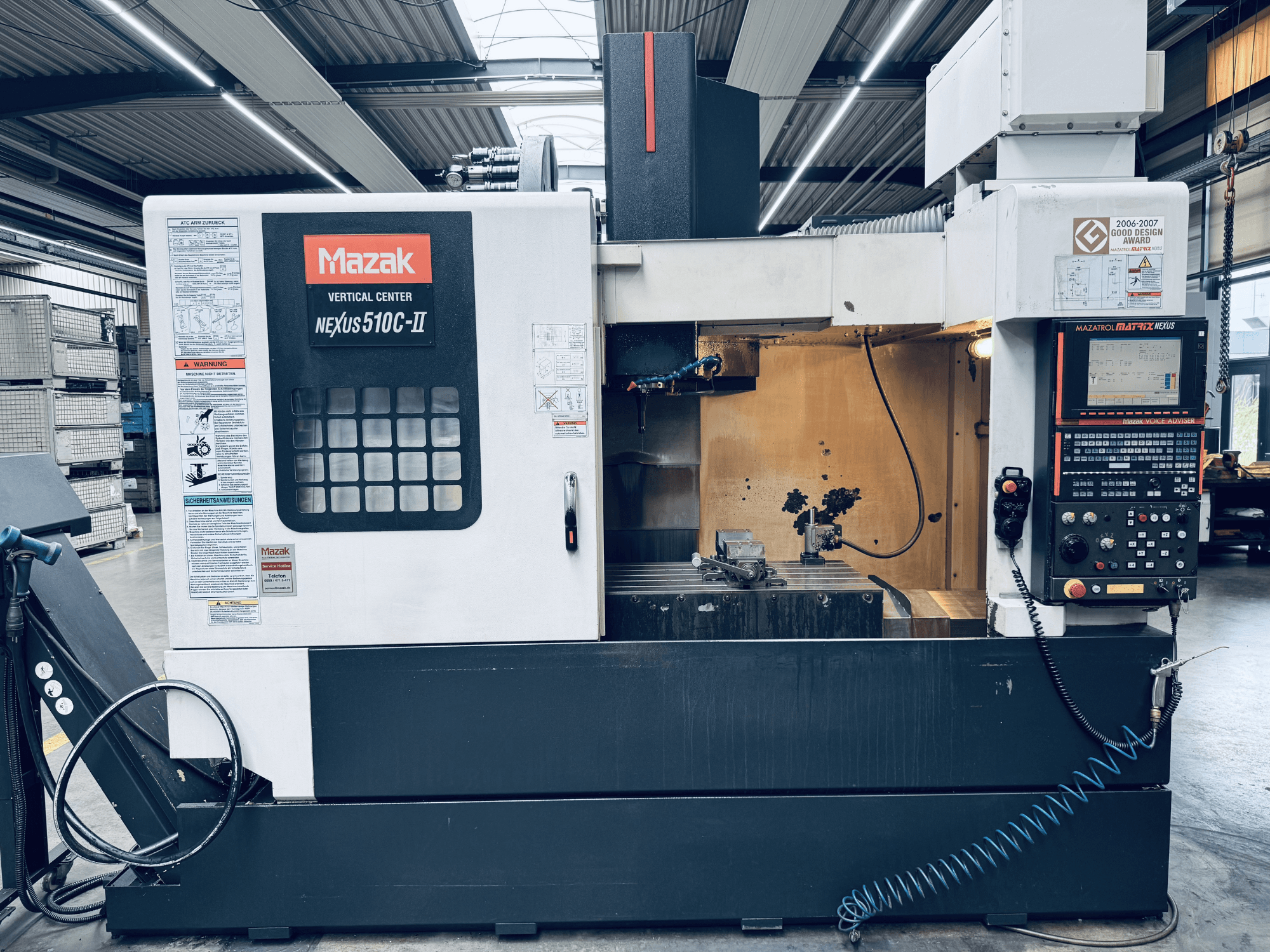 Mazak Vertical Center Nexus 510C-II, vooraanzicht, met weergave van het bedieningspaneel, het werkgebied en de bedieningsfuncties in een werkplaatsomgeving.