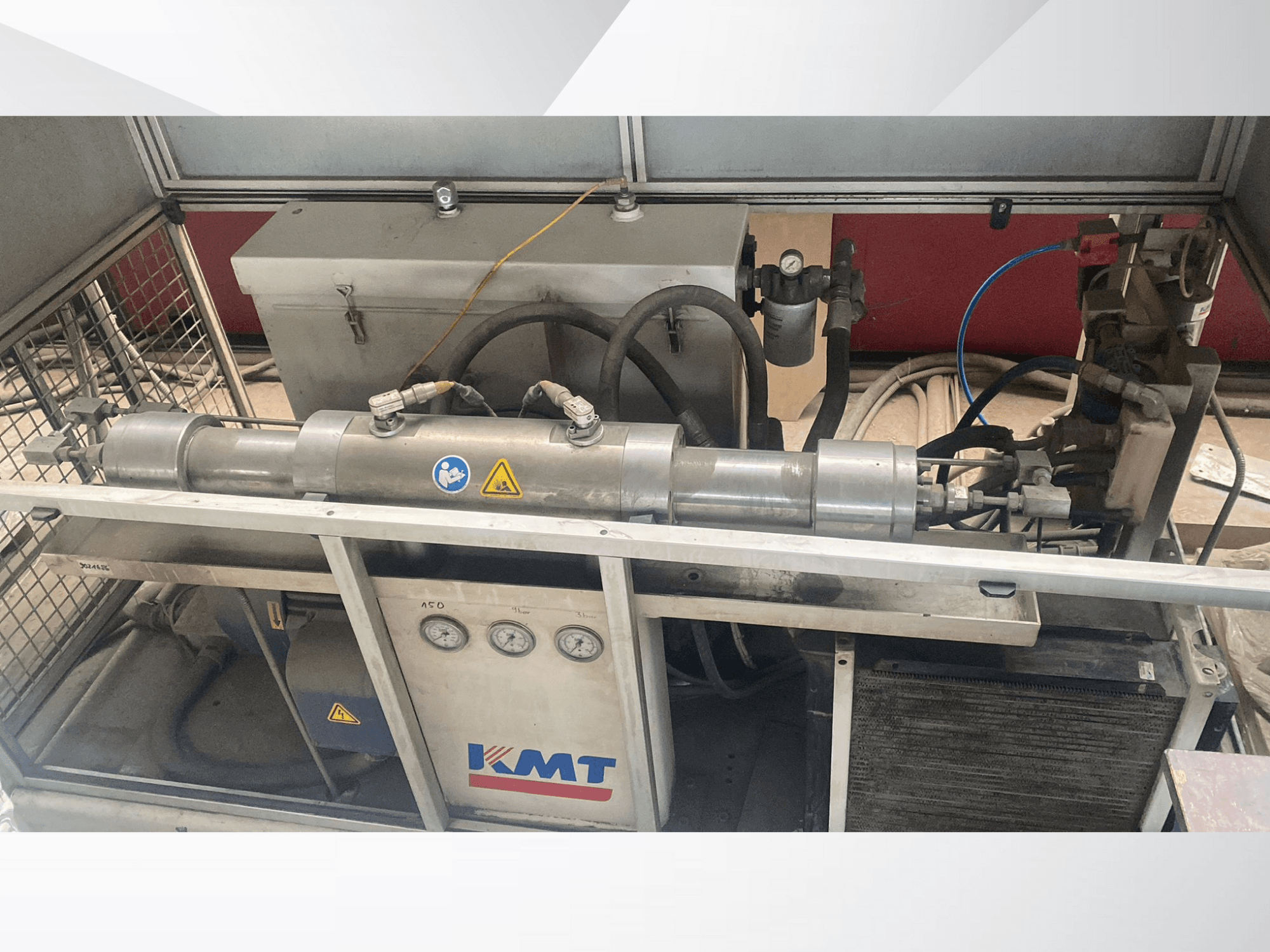 KMT hydraulische machine in vooraanzicht, met drukmeters, slangen en een metalen behuizing, ideaal voor industriële toepassingen.