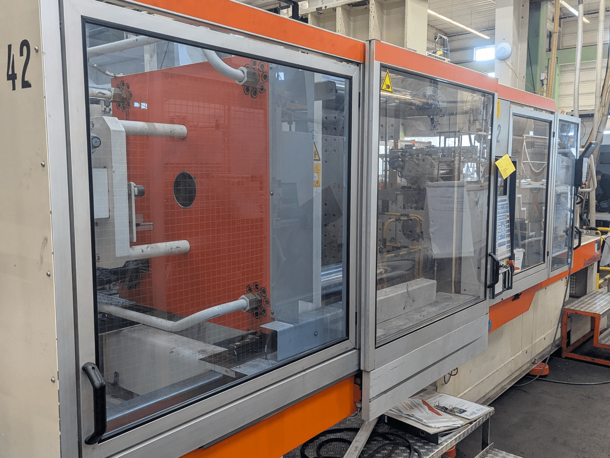 Krauss Maffei KM 350-3000 hydraulische spuitgietmachine, zijaanzicht met bedieningselementen en interne onderdelen achter glas.
