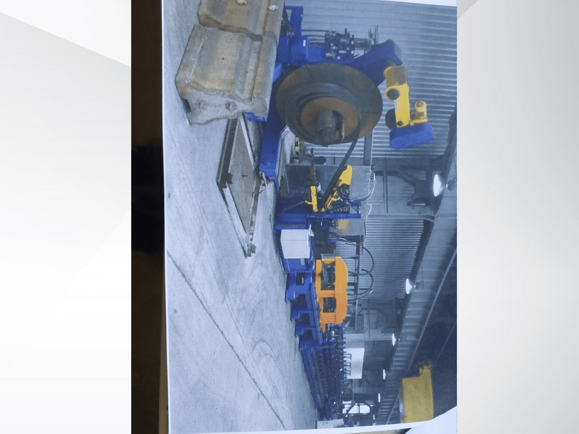 Een Müller Profilierung 3-profielbuigmachine in een werkplaats, met een blauw frame en gele hydraulische onderdelen.