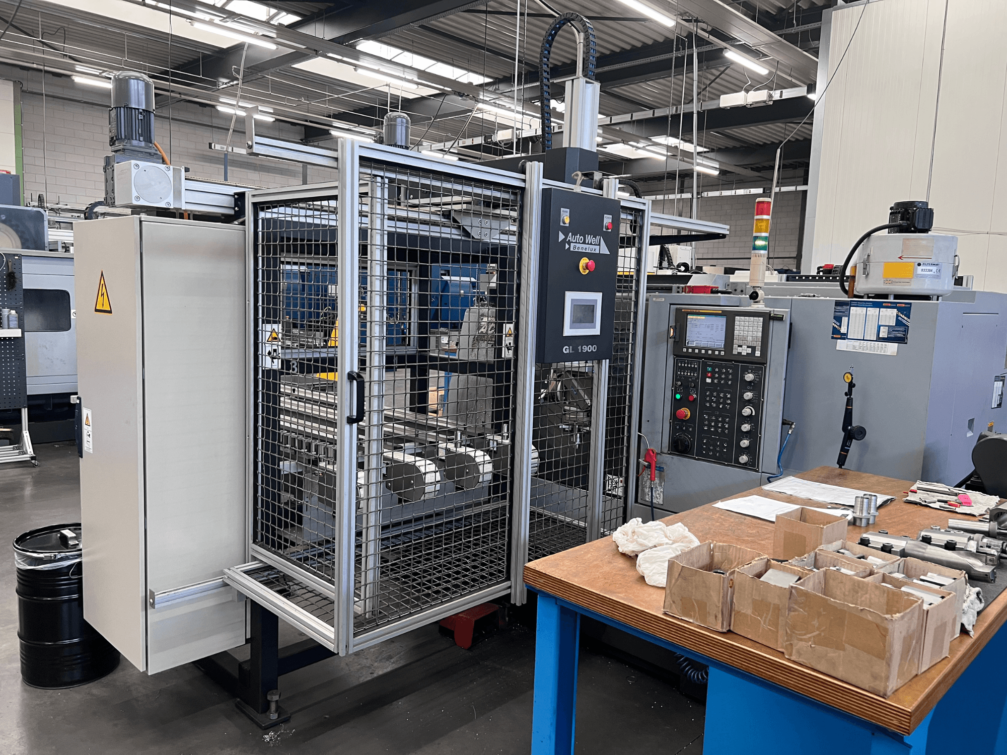 Vooraanzicht van Auto Weld GL 1900 machine met bedieningspaneel, veiligheidsbehuizing en omliggend gereedschap op een werkbank.