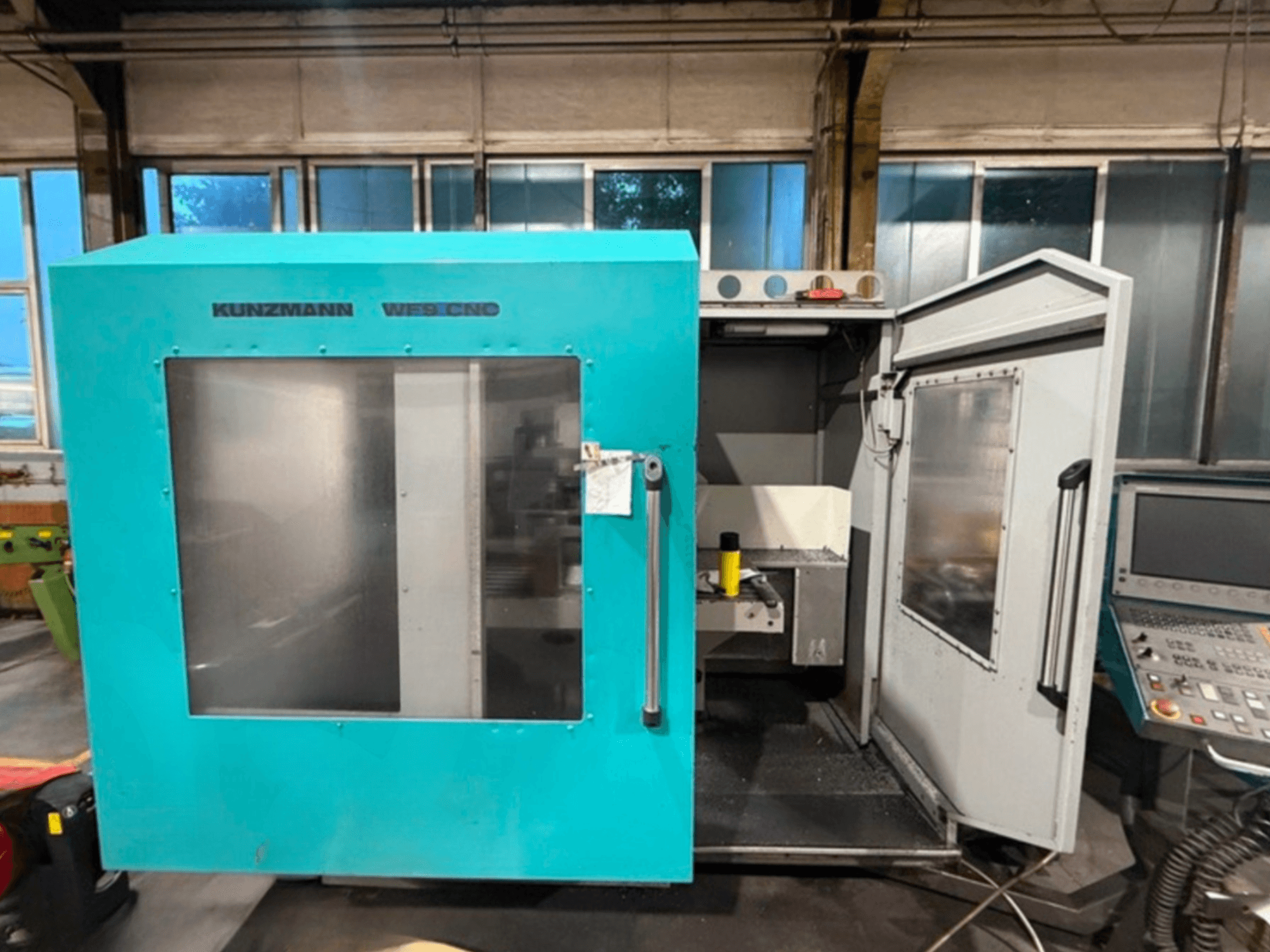 KUNZMANN WF9 CNC verticaal bewerkingscentrum, vooraanzicht met open deuren, waarin het interieur en het bedieningspaneel te zien zijn.