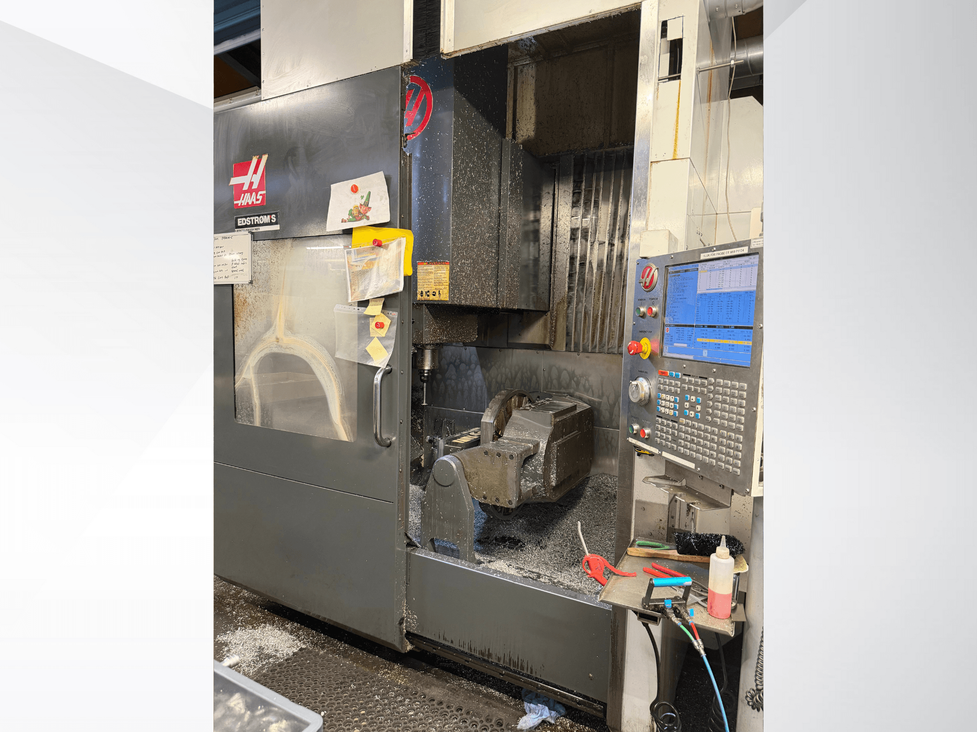 Haas CNC machine model EDSTROM S, vooraanzicht, met metalen werkstuk, bedieningspaneel en metaalschilfers binnenin.