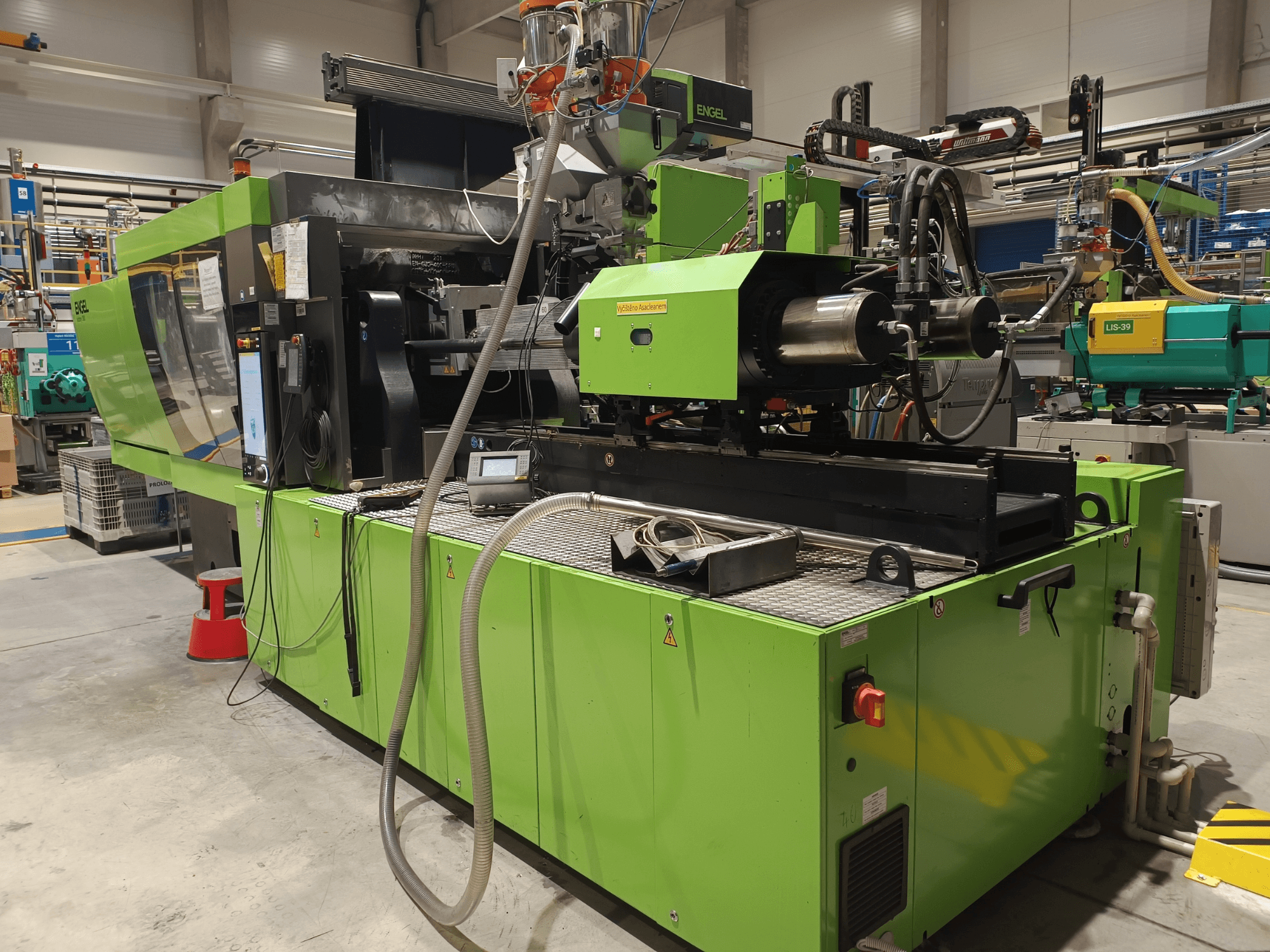 Engel spuitgietmachine, zijaanzicht, groene buitenkant, met touchscreen paneel en hydraulische componenten zichtbaar.