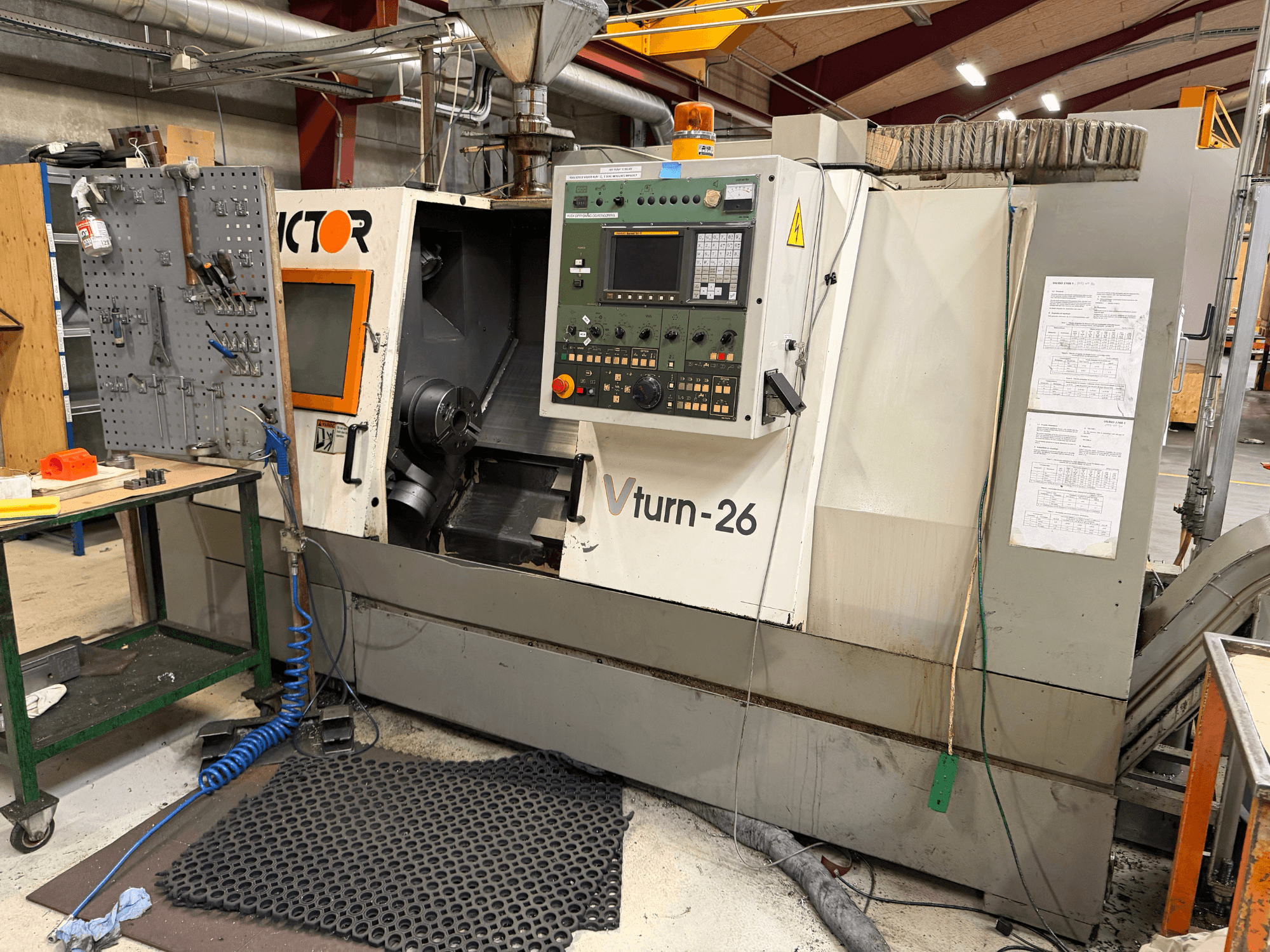 De horizontale draaimachine Victor VTurn-26, gezien van voren, toont het bedieningspaneel en de bedieningsonderdelen in een werkplaatsomgeving.