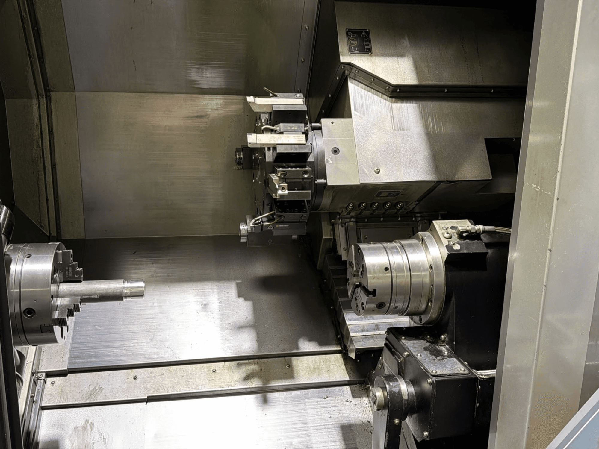 Binnenaanzicht van het Hurco TMX8MYS draai-freescentrum, met daarin de spil, de spanklauw en de gereedschapshouder met metalen oppervlakken.