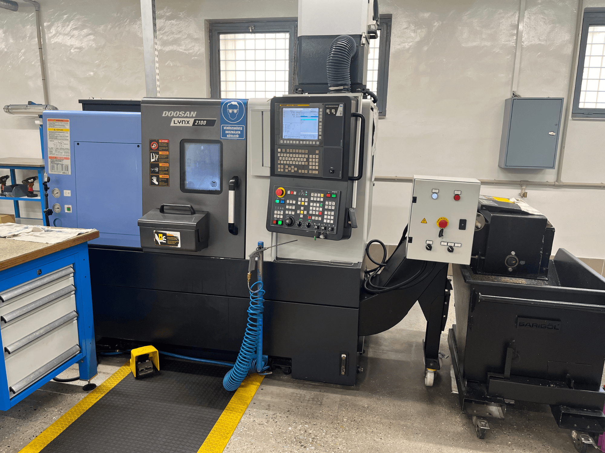 Doosan Lynx 210 draaibank in werkplaats, met het bedieningspaneel, de gereedschapopslag en het koelsysteem, zijaanzicht met details van de werkruimte.