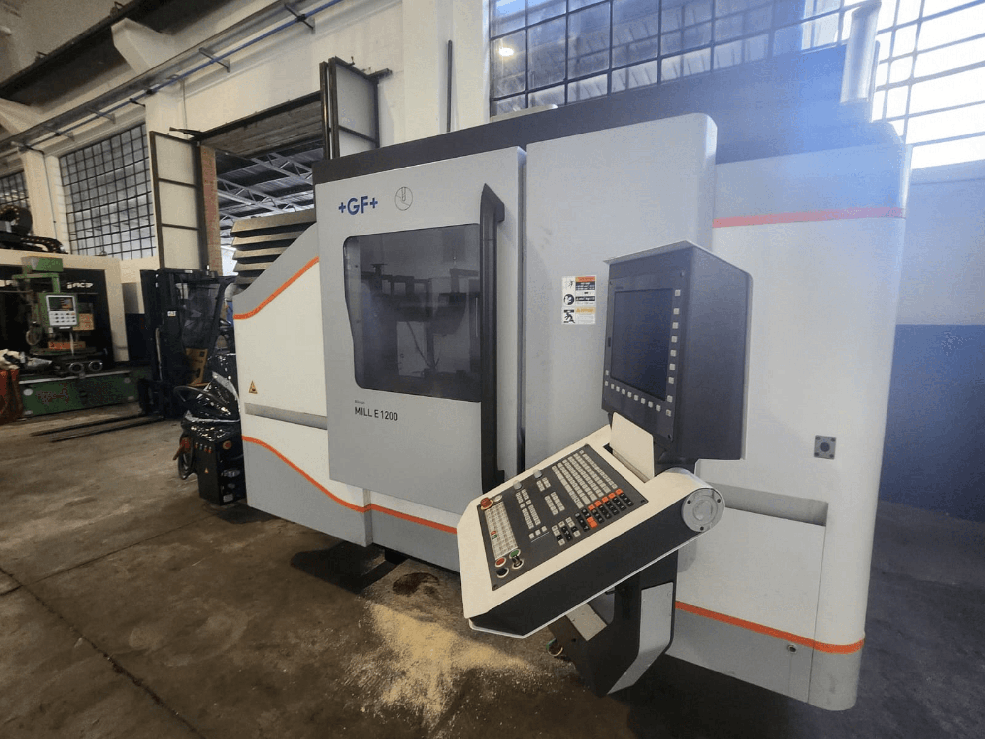 GF MILL E1200, vooraanzicht van freesmachine met bedieningspaneel, scherm en veiligheidslabels, in werkplaatsomgeving.