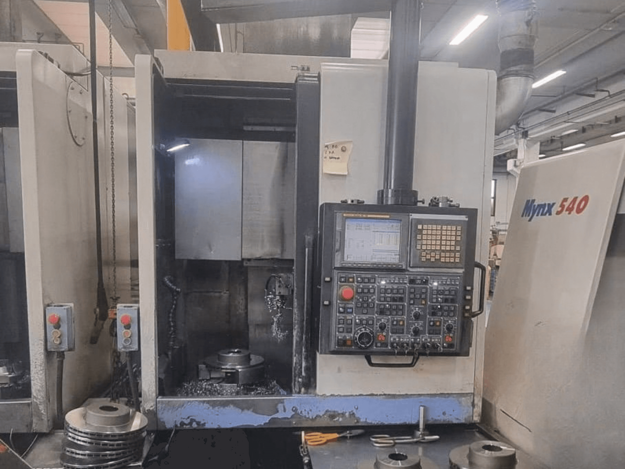 Vooraanzicht van een DOOSAN PUMA V400-2SP verticale draaimachine, met het bedieningspaneel en de opstelling van het werkstuk in de machine.