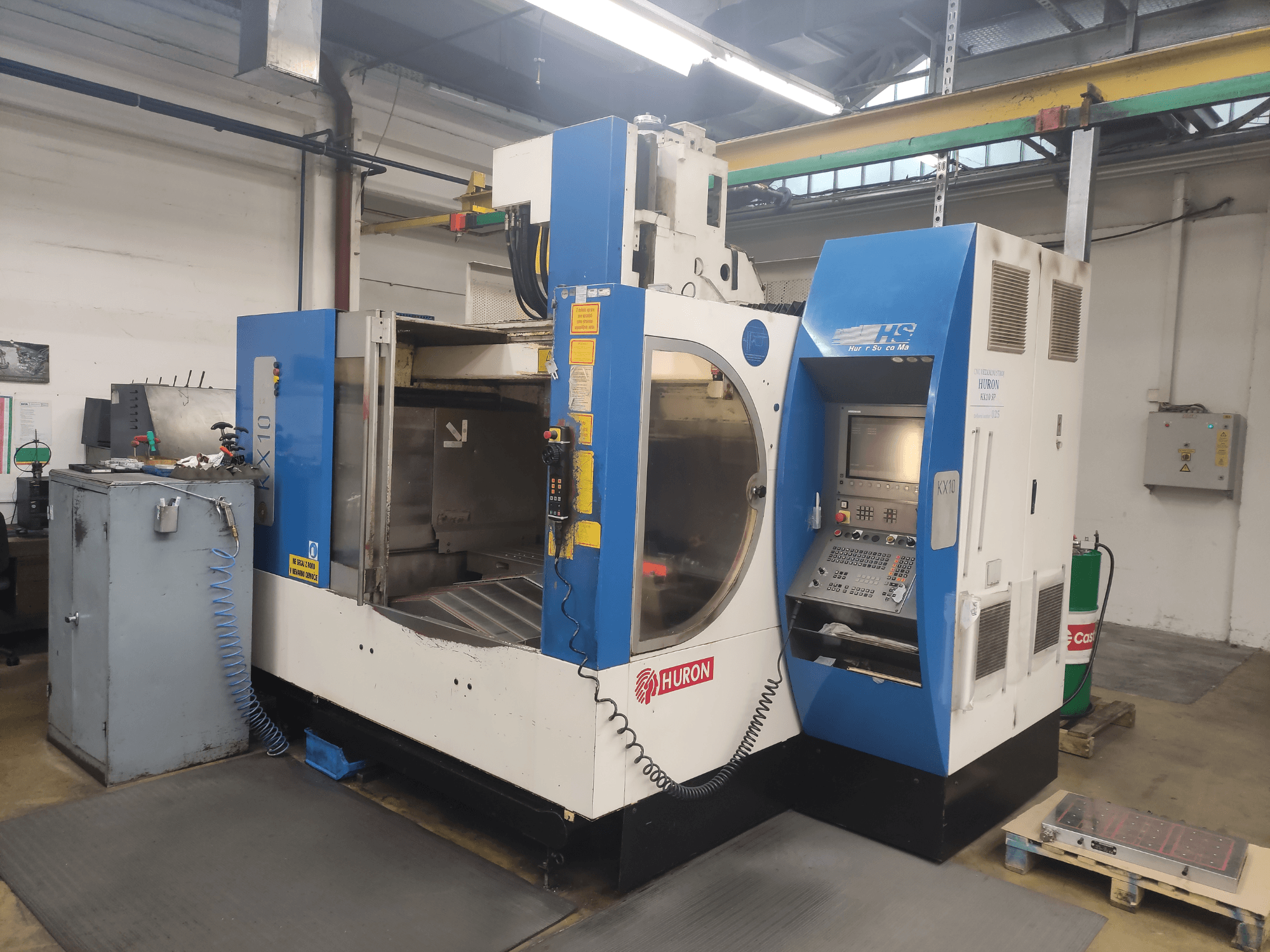 HURON KX10 CNC machine in een werkplaats, vooraanzicht, met bedieningspaneel en grote opening voor bewerking.