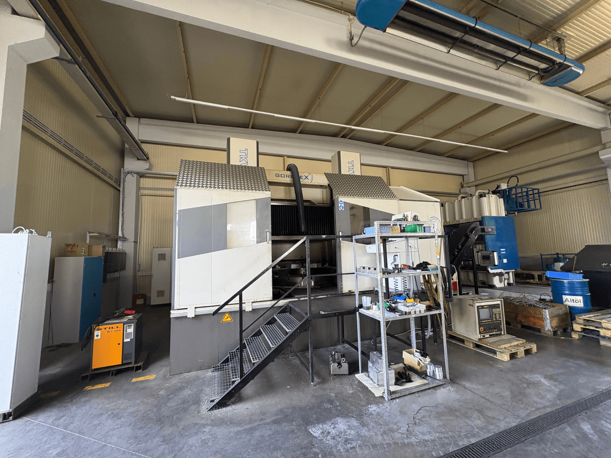 Industriële bewerkingsopstelling met GORAT X machine, zijaanzicht; inclusief gereedschappen, bedieningspaneel en apparatuur op rekken.