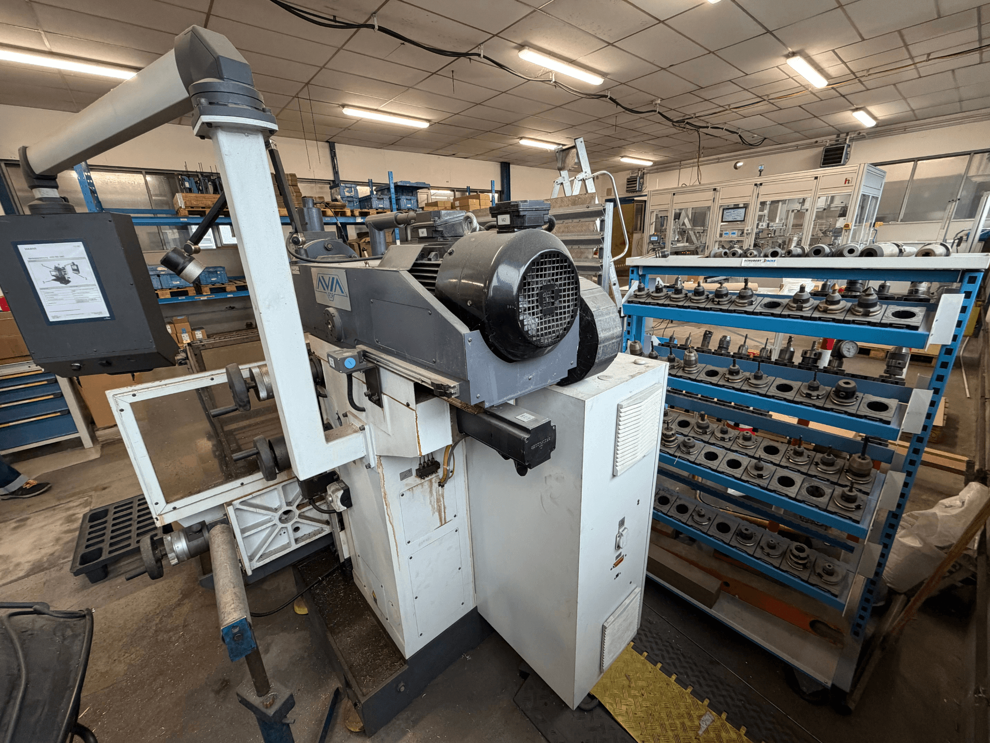Avia FNX30NC universeel bewerkingscentrum, vooraanzicht met bedieningselementen en gereedschapopslagruimte, met onderdelen op de achtergrond.