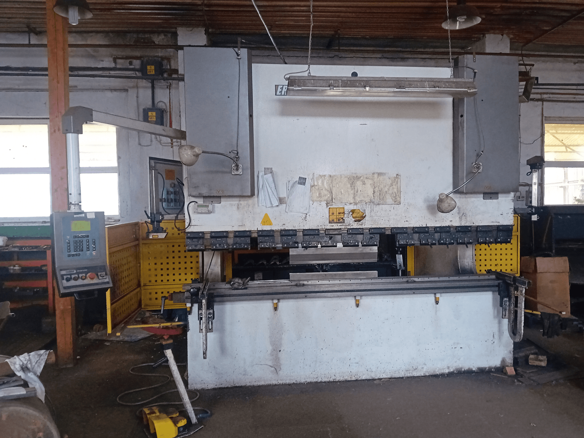 ERMAK CNC HAP 3100x300 hydraulische pers in vooraanzicht, met bedieningspaneel en werkbank in een werkplaats.