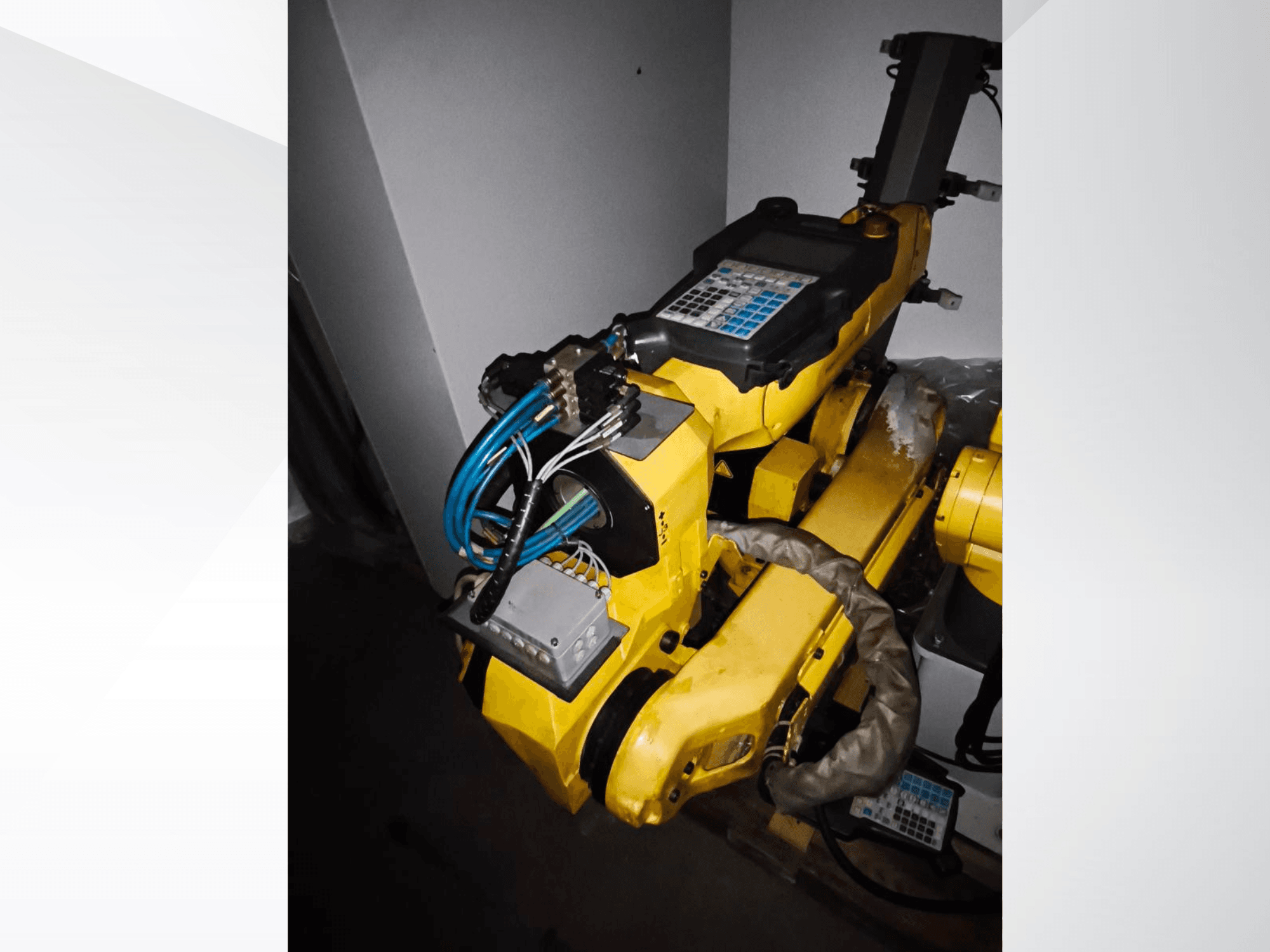 FANUC M-20iA robotarm in zijaanzicht, met geel lichaam, controlepaneel en aangesloten bedrading.