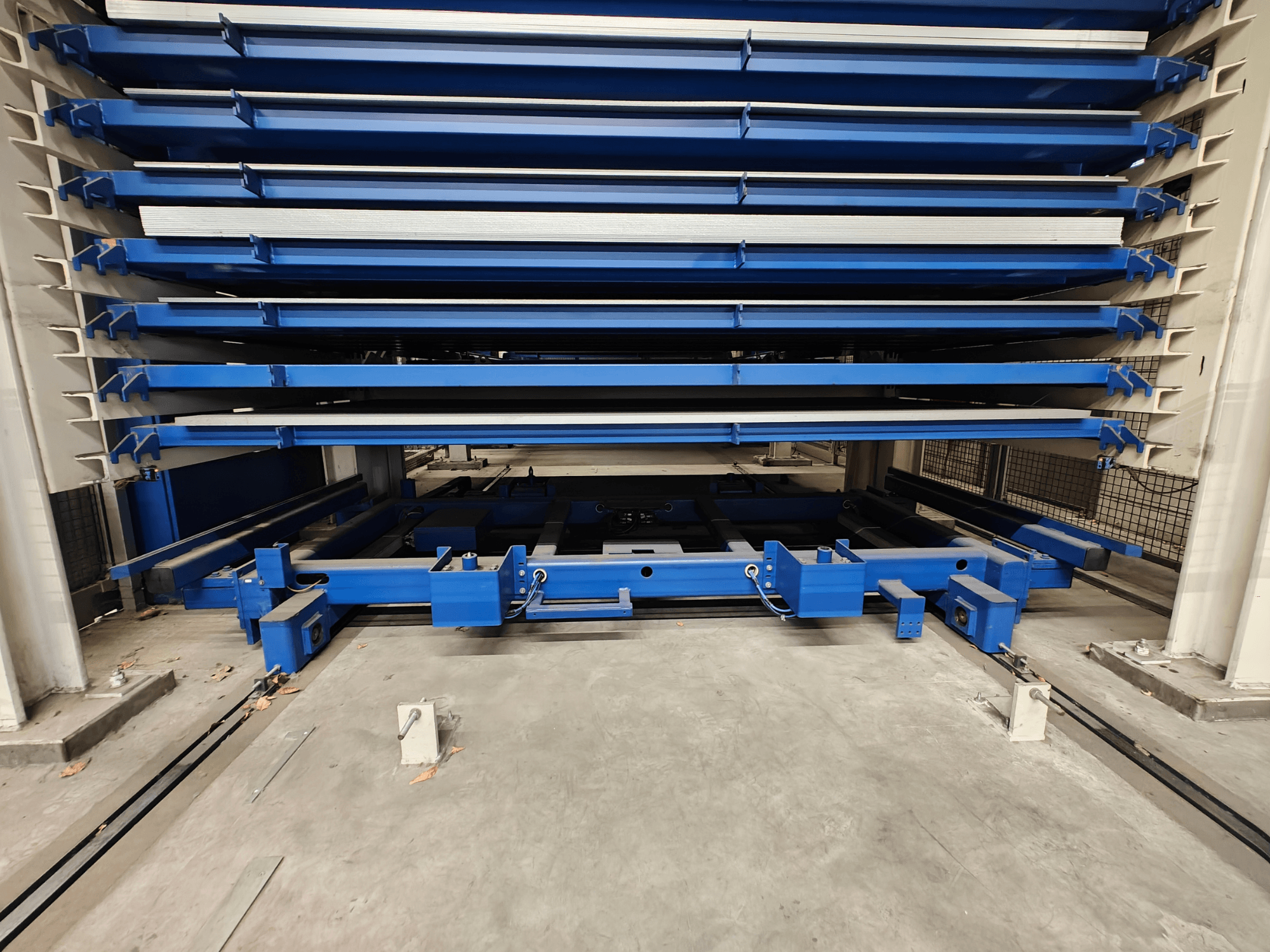 Blauw industrieel opslagrek met meerdere horizontale planken, gezien vanaf de voorkant. Voorzien van hefmechanisme en steunbalken.