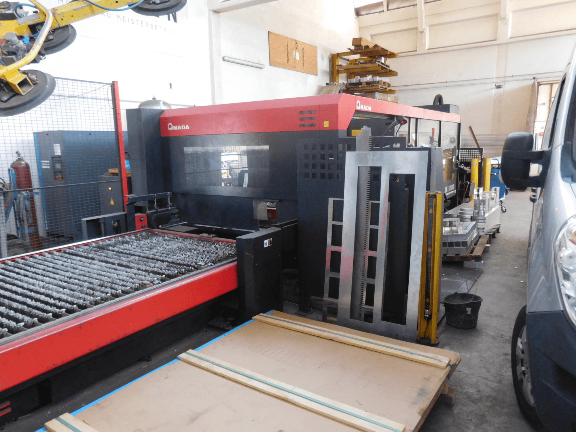 Vooraanzicht van AMADA FO-3015 II RI CO2 lasersnijmachine, met snijbed en omliggend werkgebied.