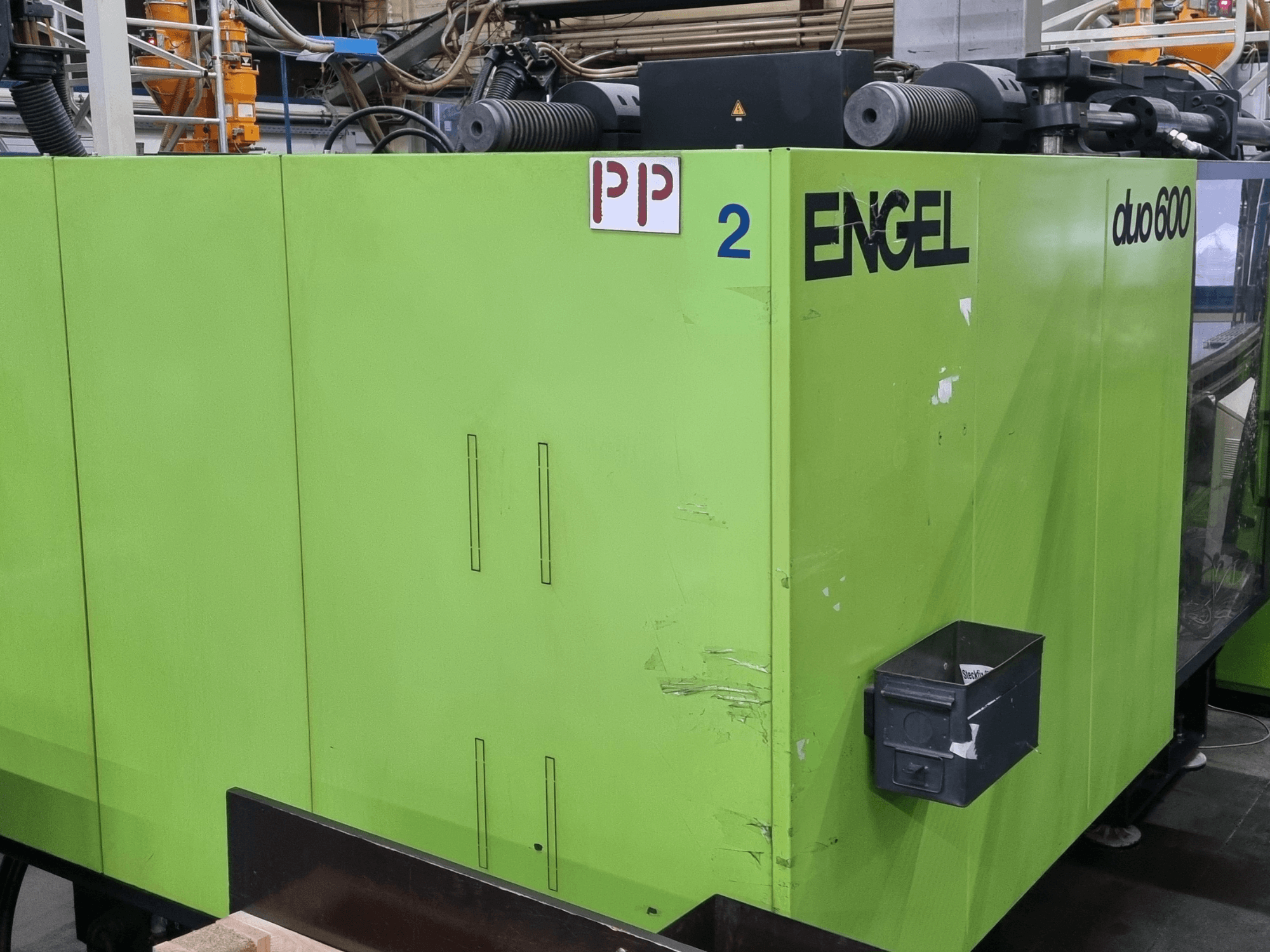Engel Duo 600 hydraulische spuitgietmachine, groene behuizing, vooraanzicht, met gelabelde onderdelen en materiaalopslagbak.