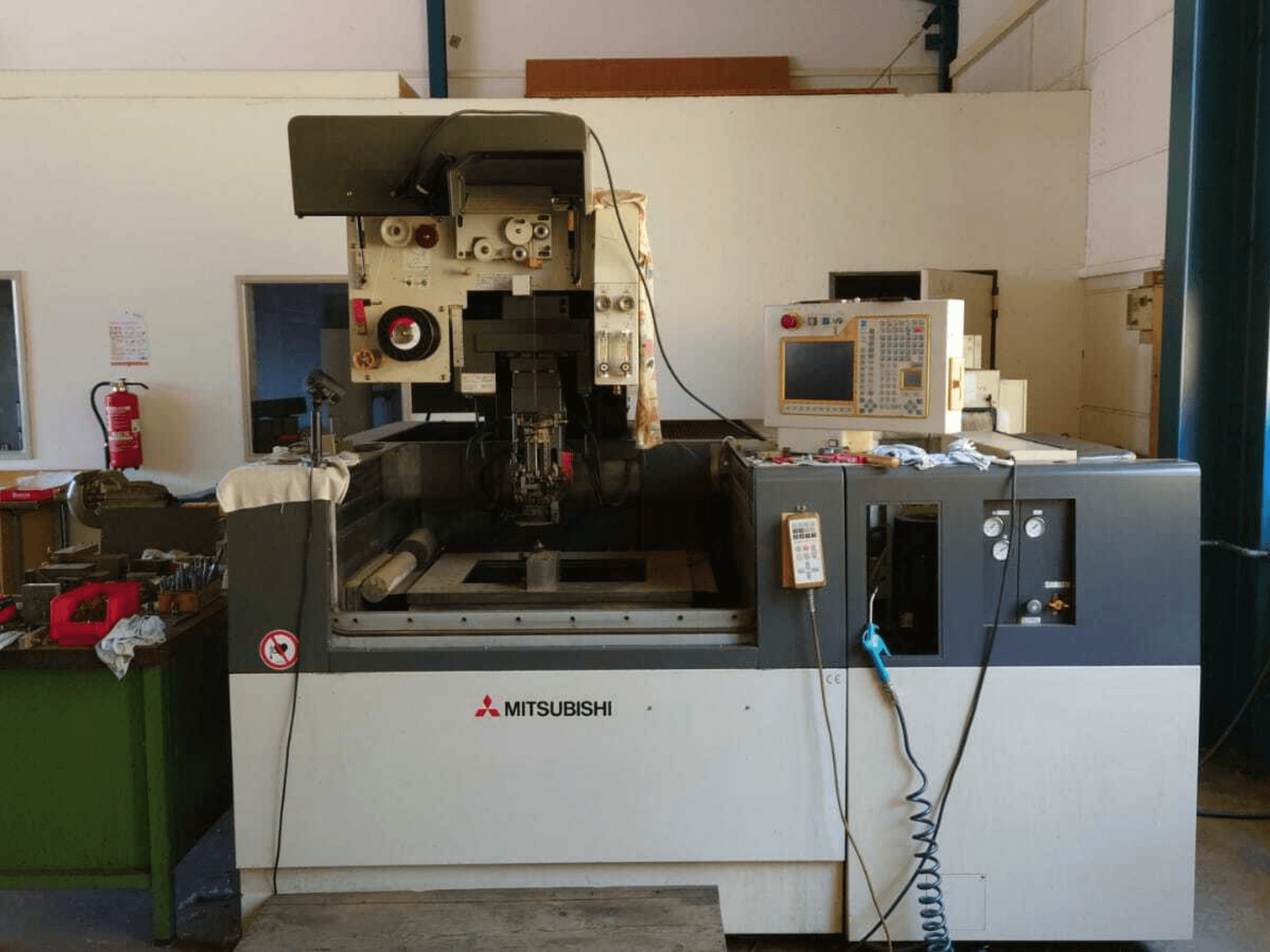 Mitsubishi FA20 draadvonkmachine, vooraanzicht met zichtbaar bedieningspaneel, werkgebied en veiligheidsborden.