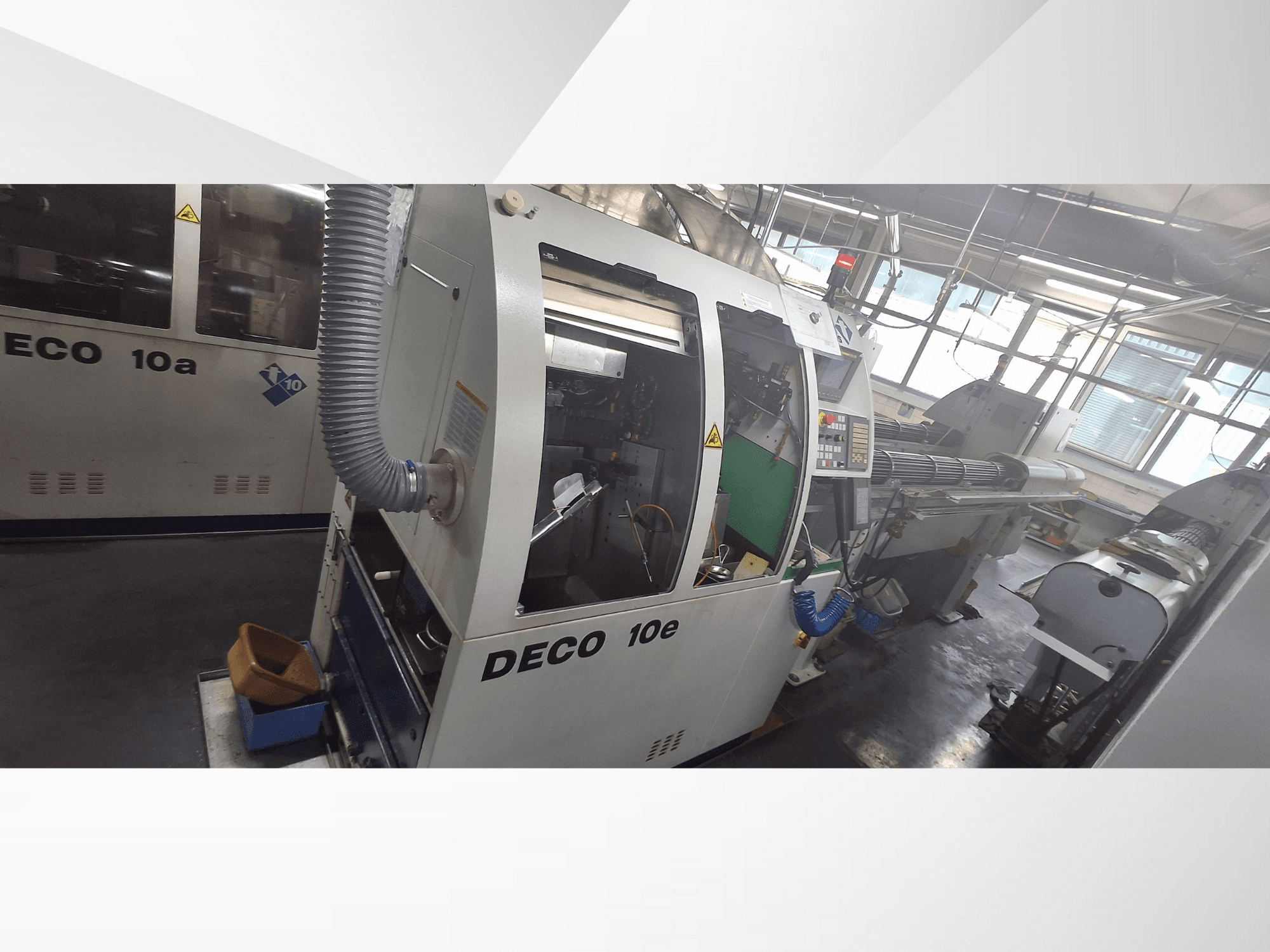 DECO 10e CNC machine in zijaanzicht, met bedieningspaneel, groen interieur en aangesloten uitlaatslang.