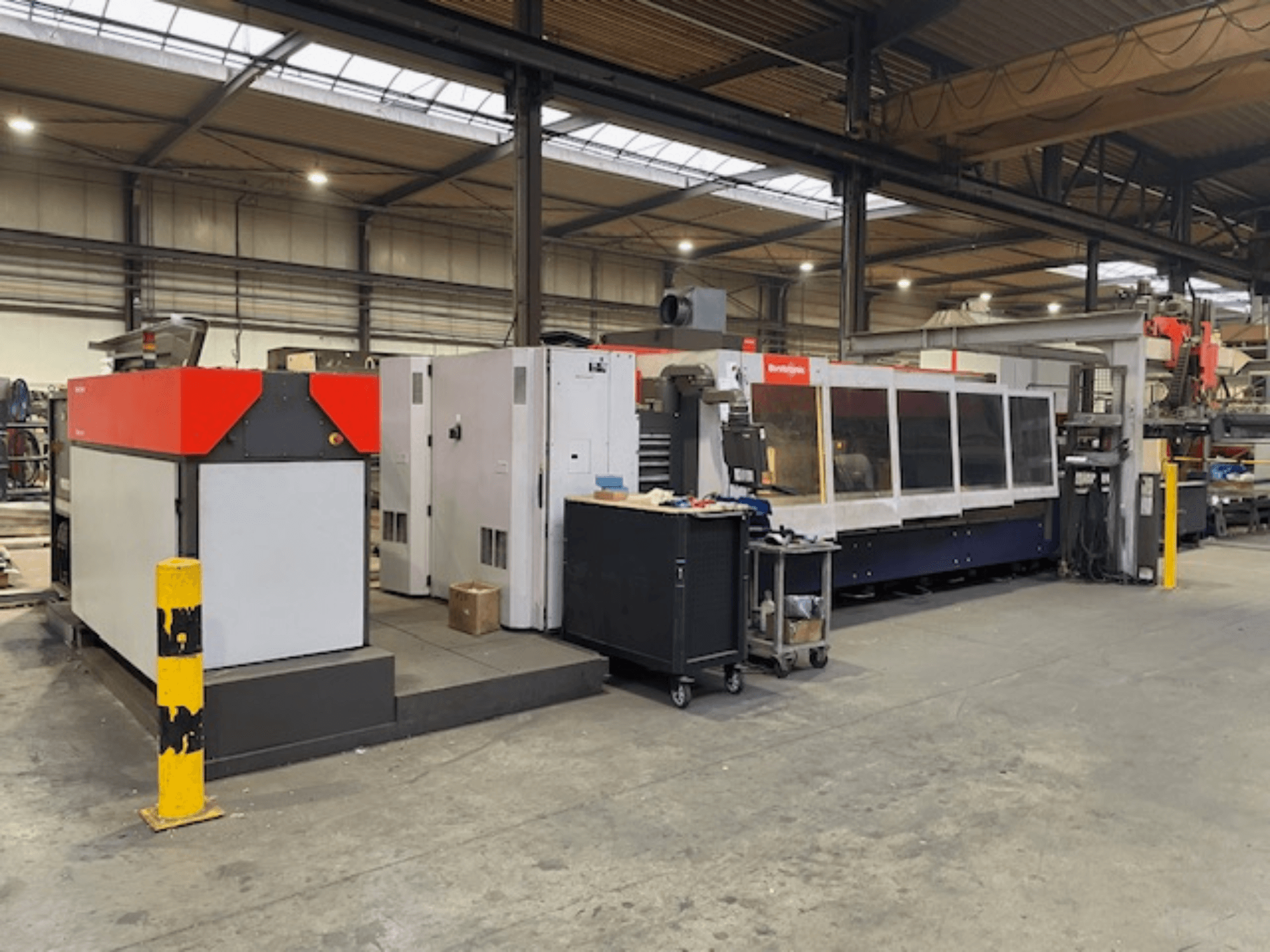 Bystronic BySpeed 3015 CO2 lasersnijmachine, zijaanzicht in een werkplaats, met opvallende rode en grijze designelementen.