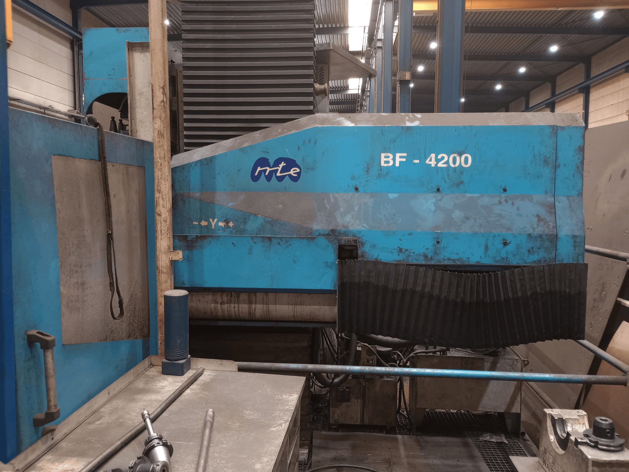 MTE BF 4200 freesmachine met bed, zijaanzicht, met blauwe behuizing en gedetailleerde machineonderdelen in een werkplaatsomgeving.