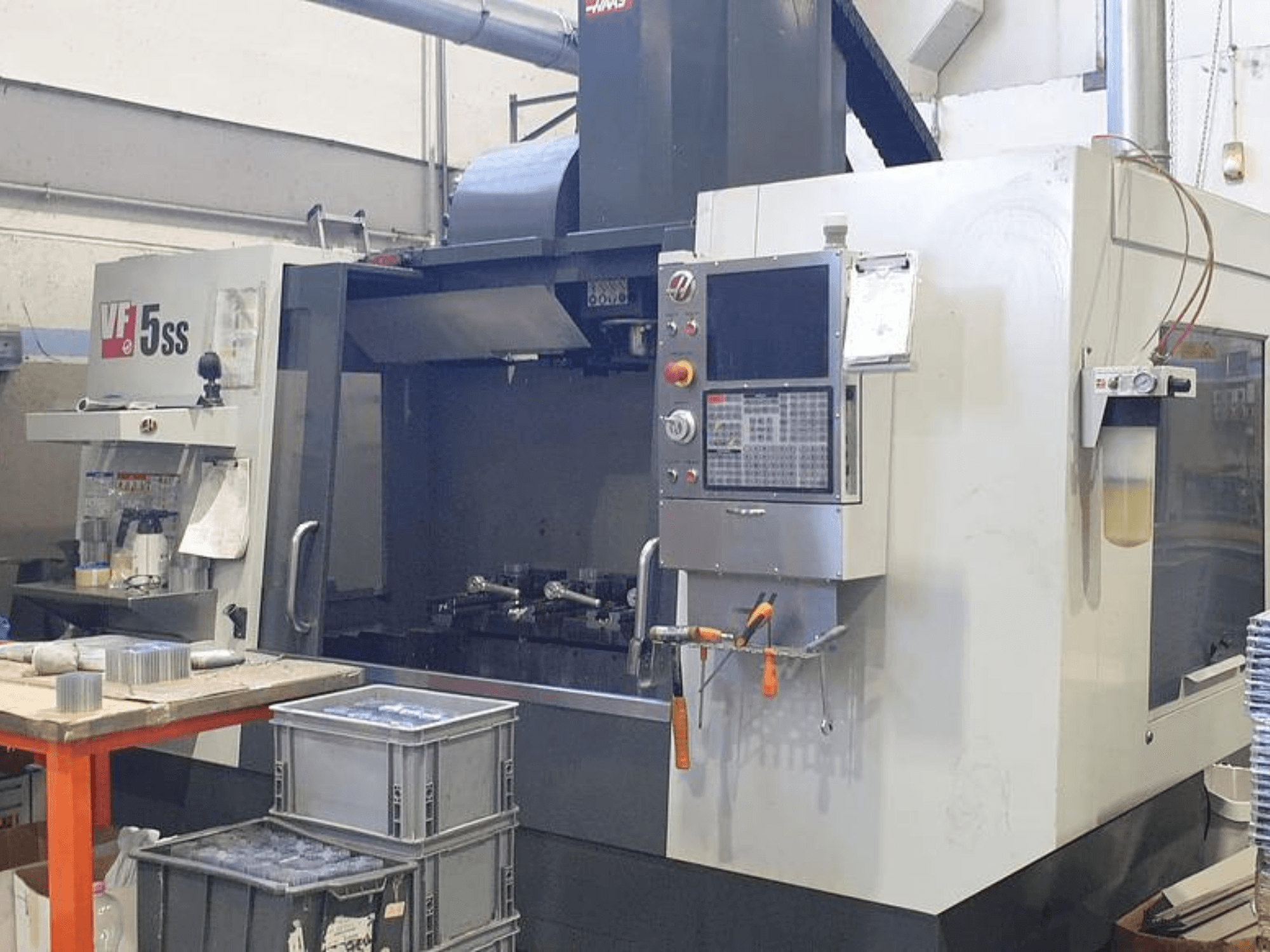 HAAS VF-5SS verticaal bewerkingscentrum in vooraanzicht, met bedieningspaneel, werkruimte en opslagbakken.
