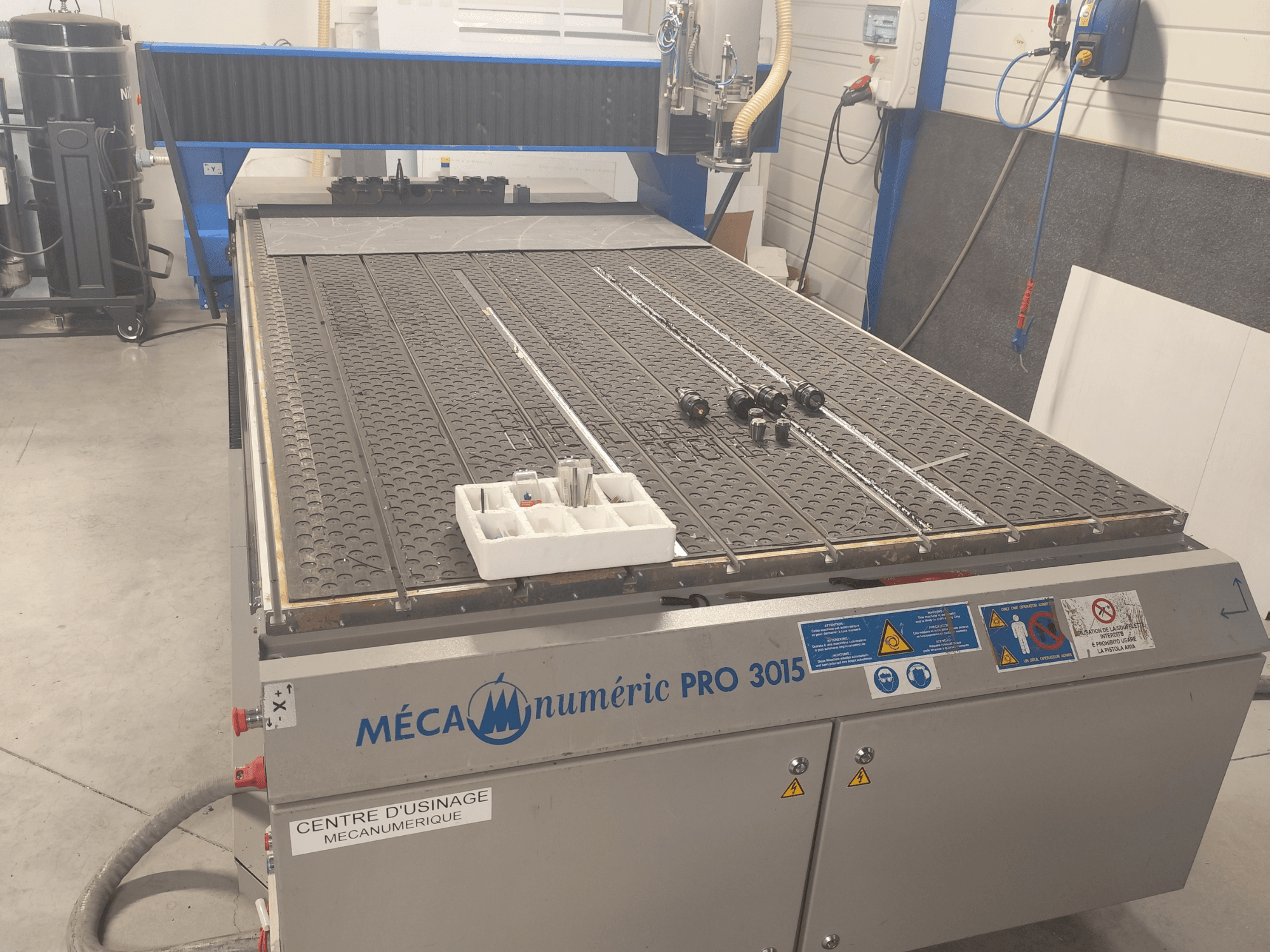 CNC-router MECANUMERIC Pro 3015, vooraanzicht, met een gedetailleerd snijplatform, bedieningspaneel en accessoires op de tafel.