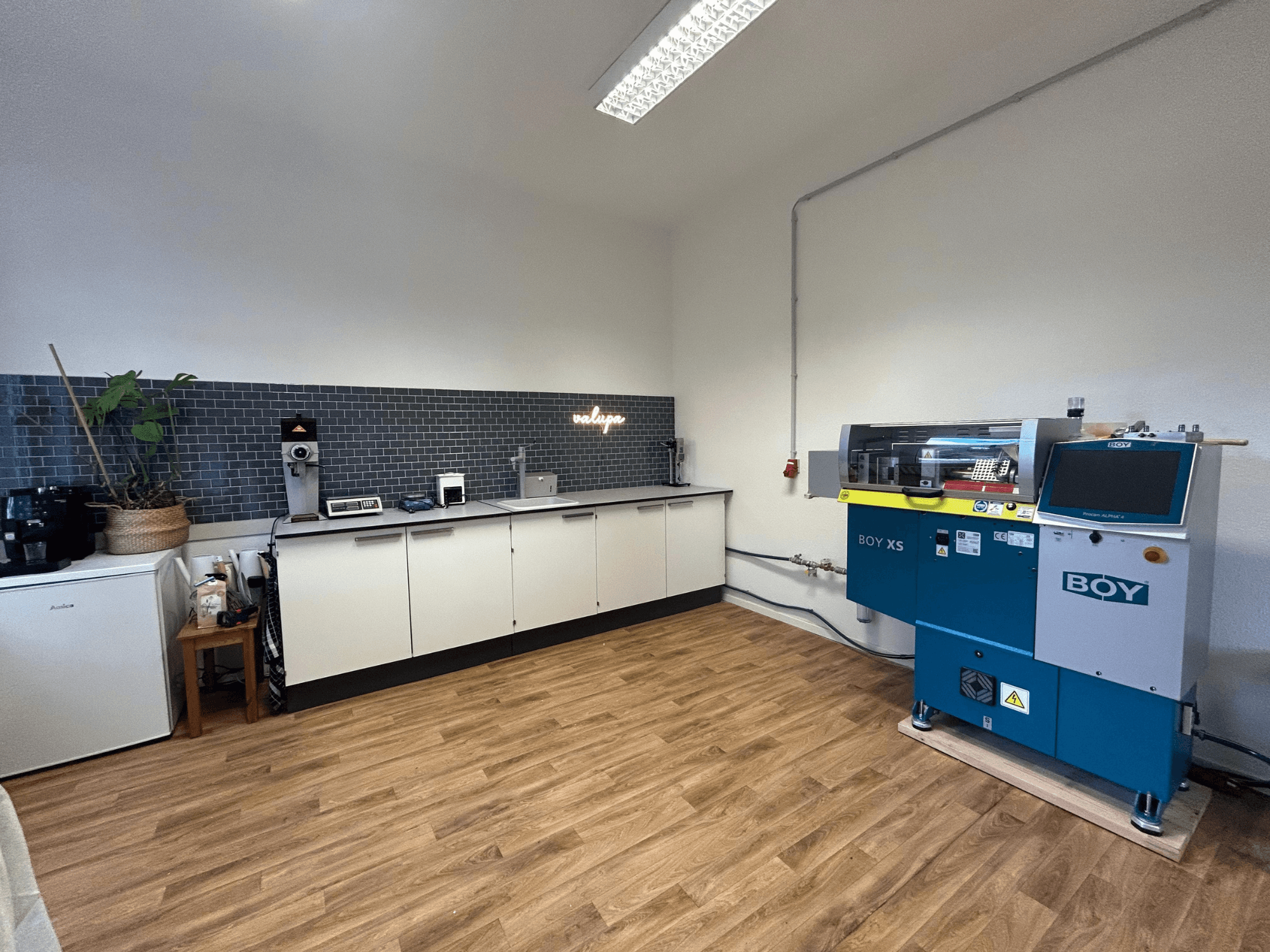 Hydraulische spuitgietmachine BOY XS 161, vooraanzicht, in een moderne keuken met apparatuur en houten vloer.