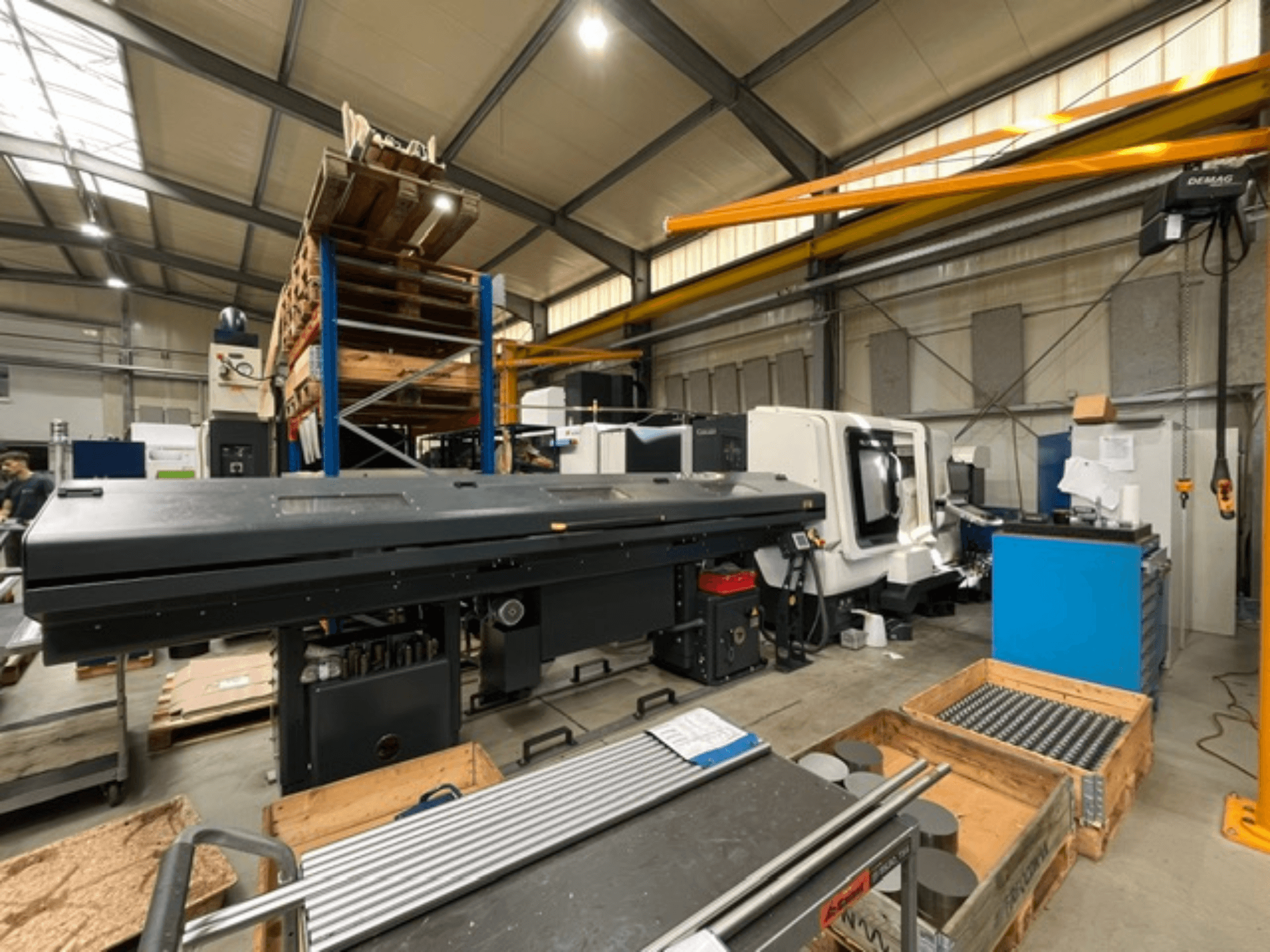 DMG MORI MORI NLX 2500/700 SY horizontale draaimachine in een fabrieksomgeving, gezien vanaf de zijkant, met zichtbare gereedschappen en pallets.