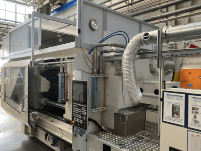 Industriële machine van Merk X, zijaanzicht met bedieningspaneel, leidingwerk en machineonderdelen in een fabrieksomgeving.
