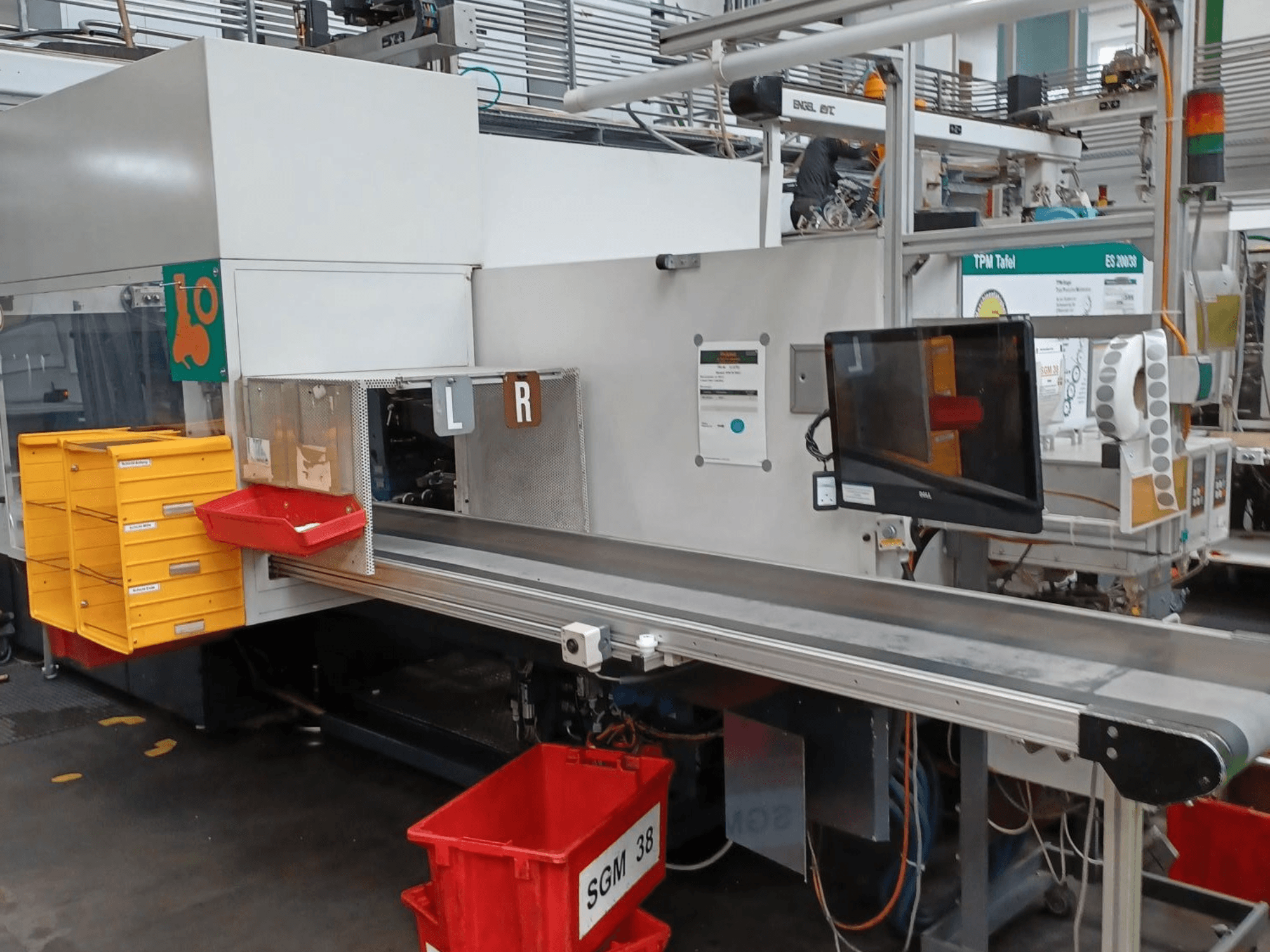 Industriële sorteermachine met gele en rode bakken, zijaanzicht, met een bedieningsmonitor en gelabelde compartimenten om te sorteren.