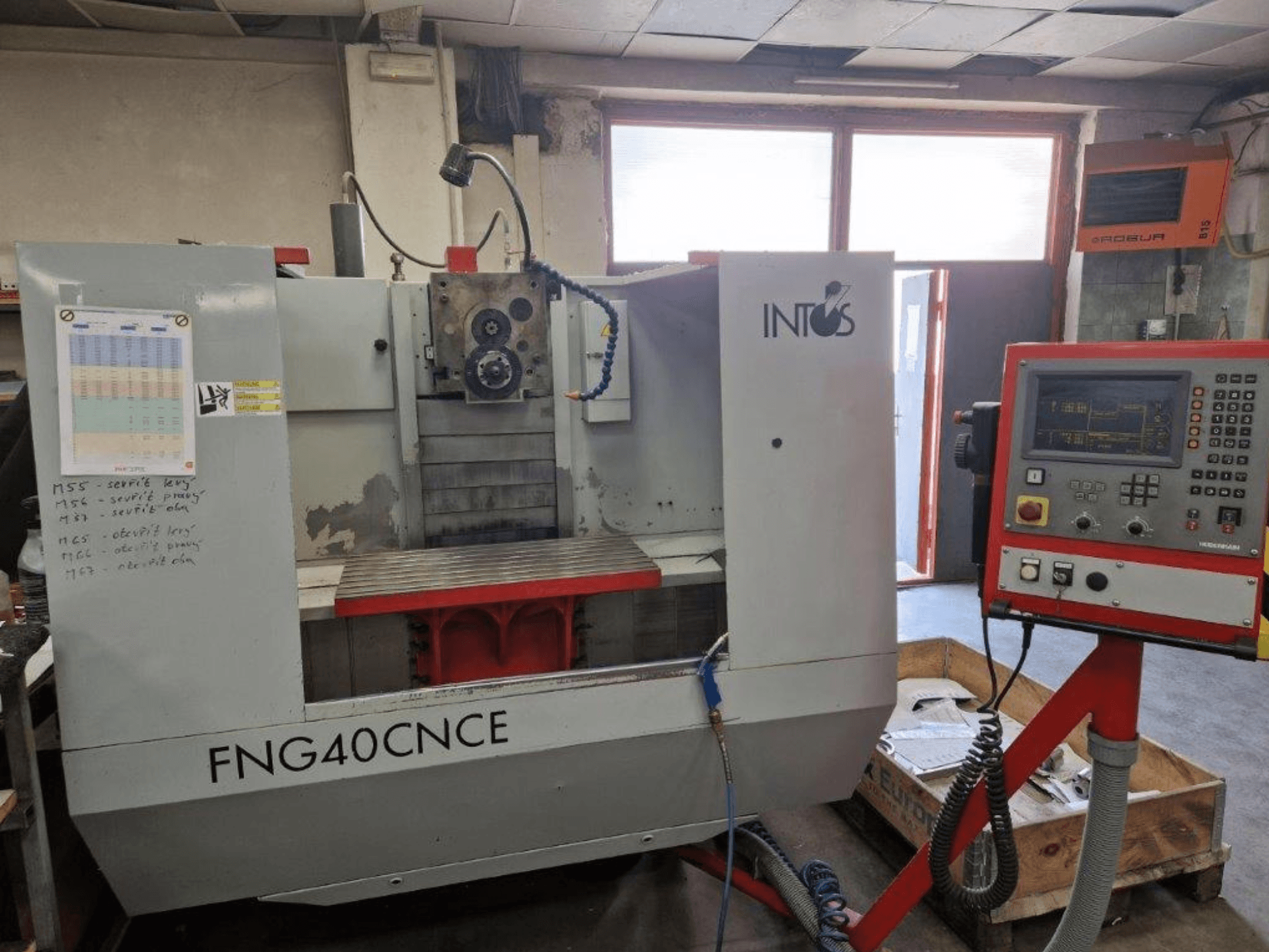 INTOS FNG40CNC machine, vooraanzicht, met bedieningspaneel, operationele onderdelen en een metalen werktafel. Ideaal voor machinale bewerking.