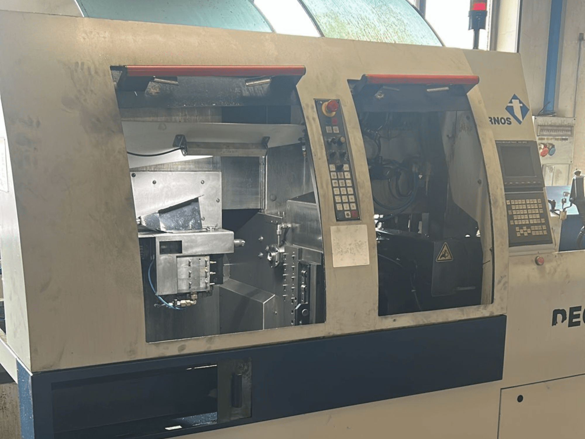 Alt-tekst: Vooraanzicht van de TORNOS Deco 13 b Zwitserse draaimachine met de bedieningspanelen en interne onderdelen zichtbaar.