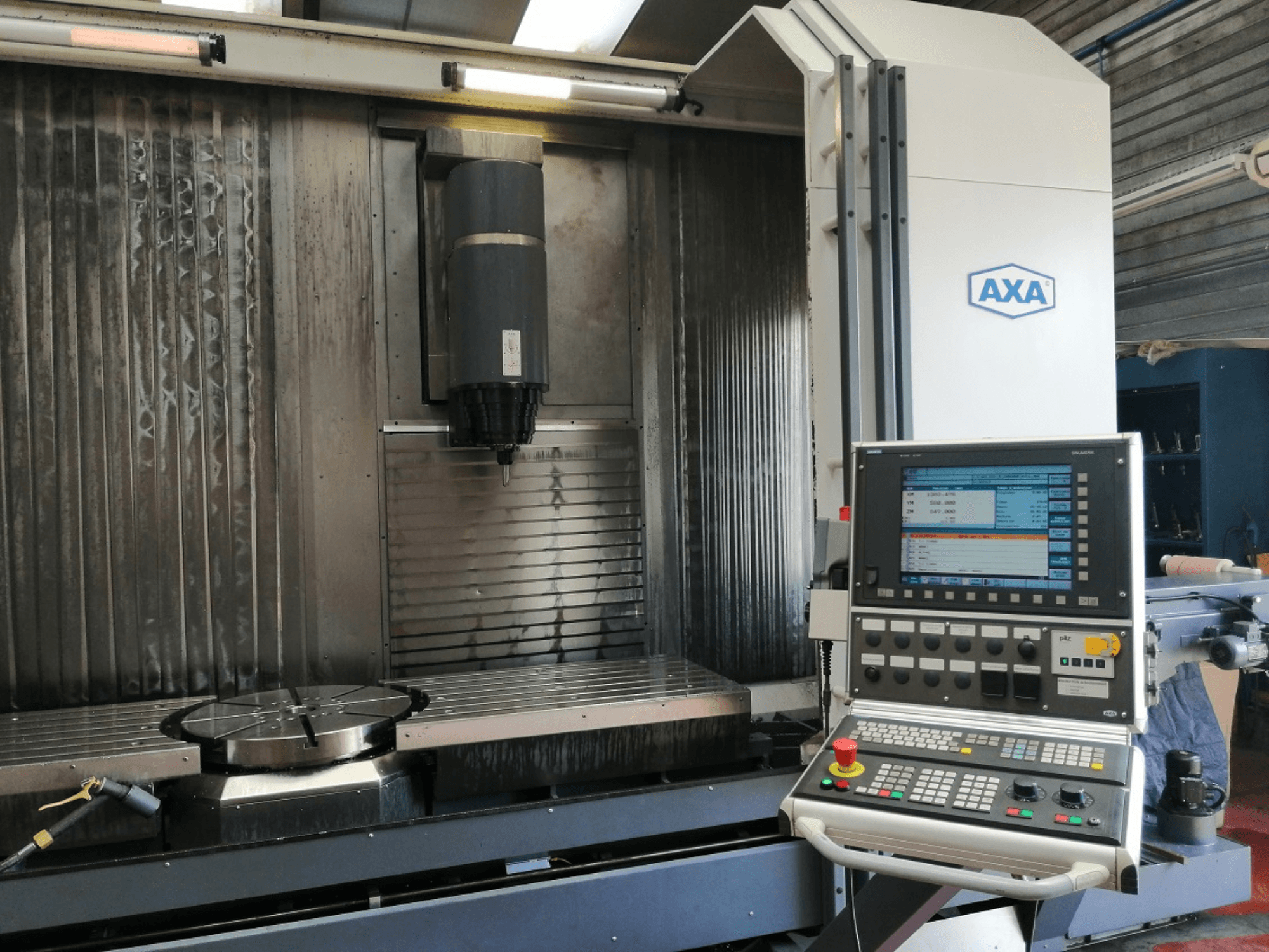 Vooraanzicht AXA CNC freesmachine met bedieningspaneel, spindel en draaitafel zichtbaar; gebruikt voor precisiebewerking.