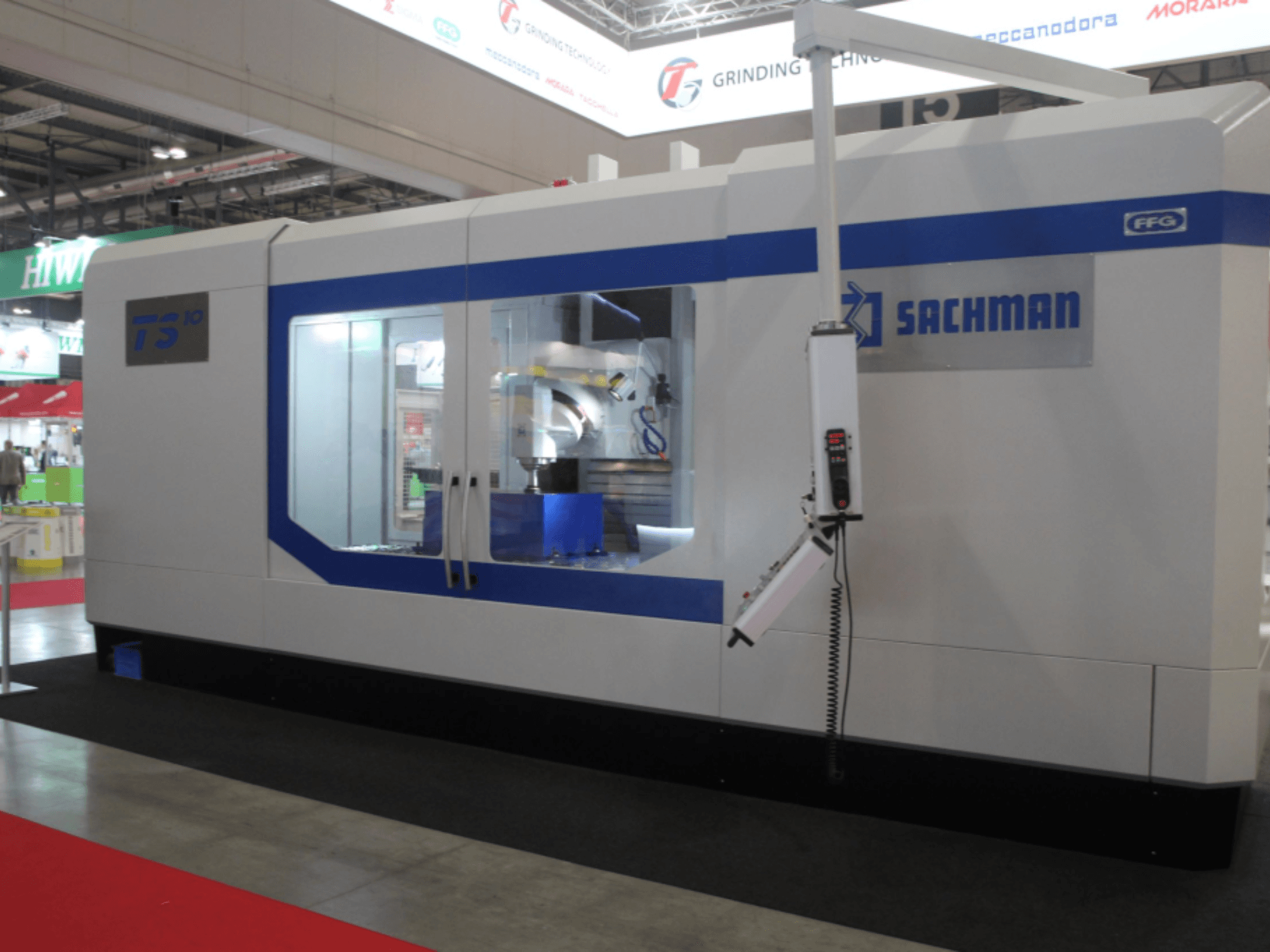 SACHMAN TS10 bedfreesmachine, vooraanzicht, met de bedieningselementen, werkruimte en slanke vormgeving op een beursvloer.