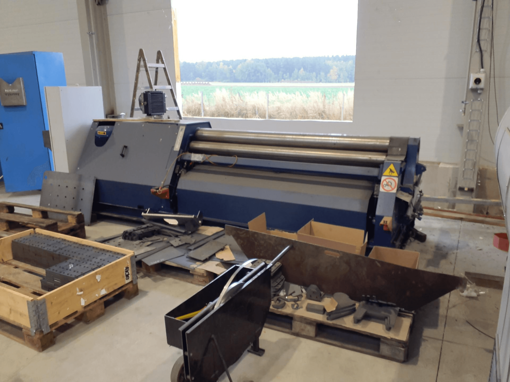 FACCIN 4HEL-2017 Plaatrolmachine in een werkplaats, vooraanzicht met verspreide metalen onderdelen en gereedschappen.