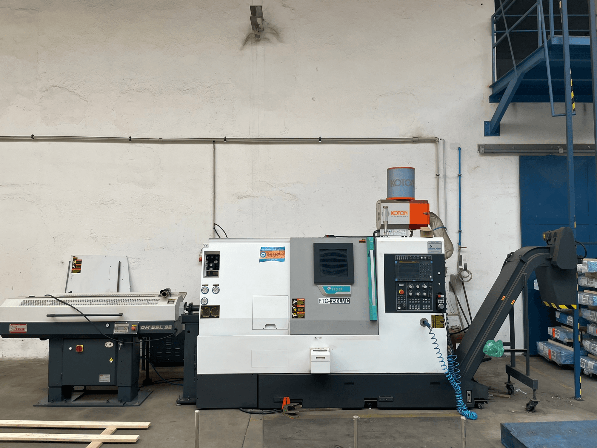 Feeler FTC 350 LMC horizontale draaimachine in een werkplaats, met het bedieningspaneel en de toevoerleidingen. Zijaanzicht.