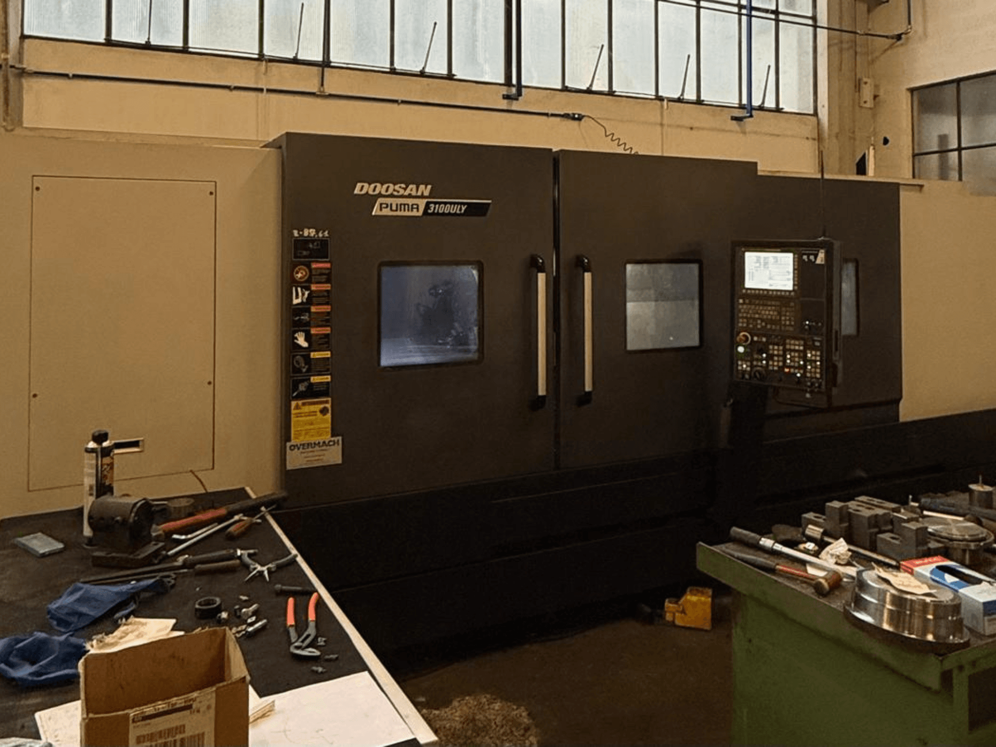 Doosan Puma 3100LY CNC draaibank in een werkplaats, zijaanzicht, met bedieningspaneel en gereedschappen zichtbaar op de werkbank.
